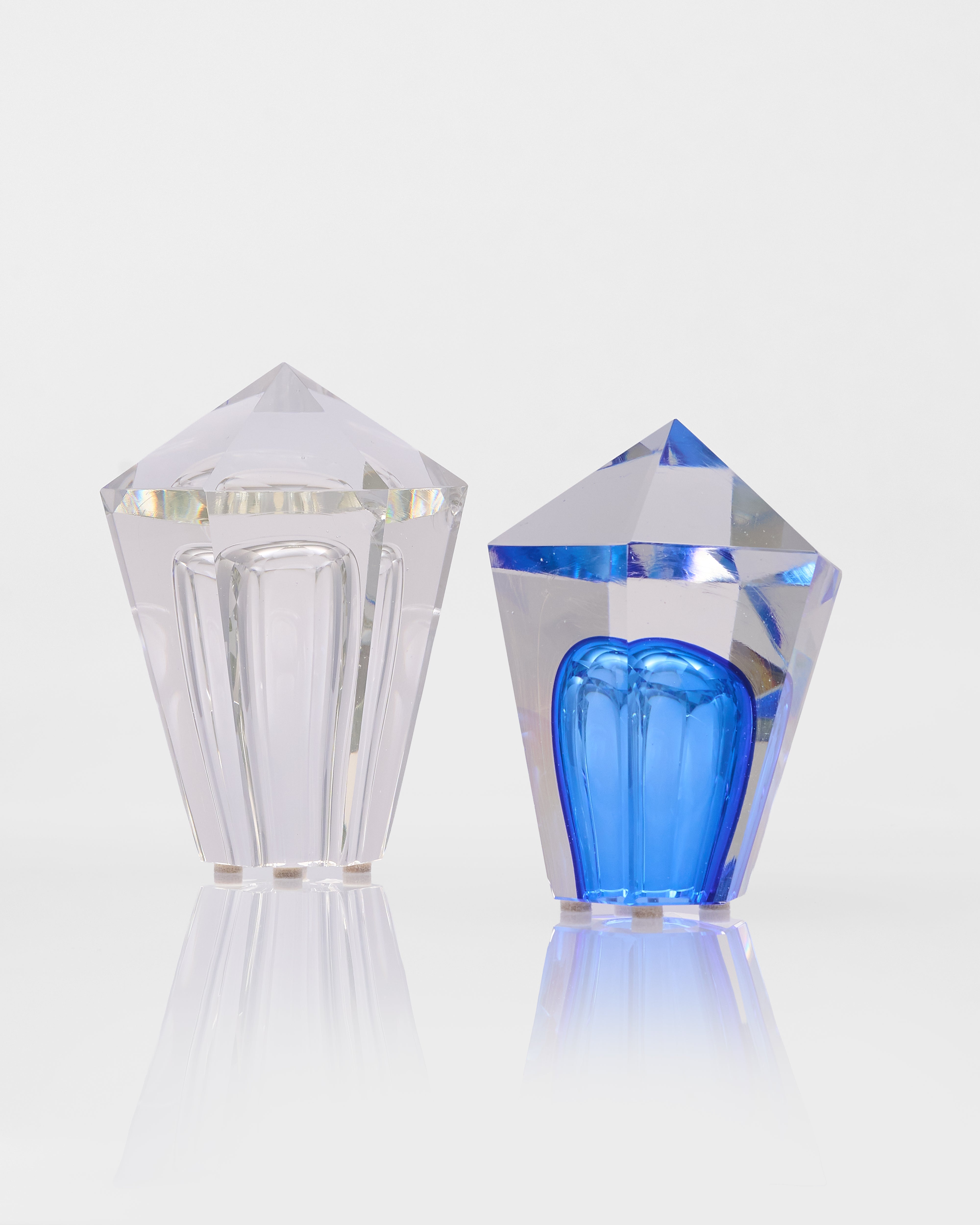 Two crystal-like objects, one clear and one with a blue interior, on a white background.