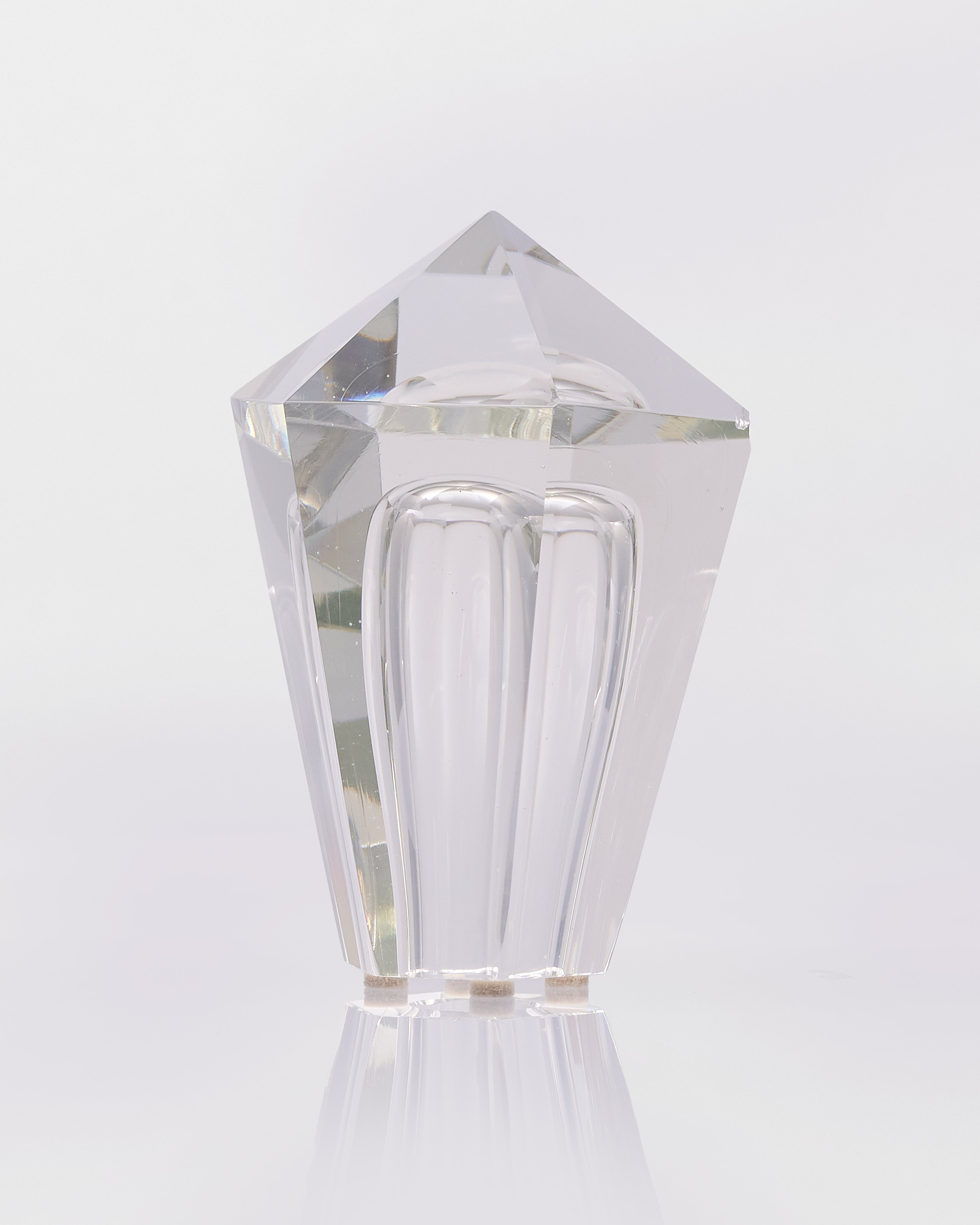 Clear glass perfume bottle with geometric design on a white background