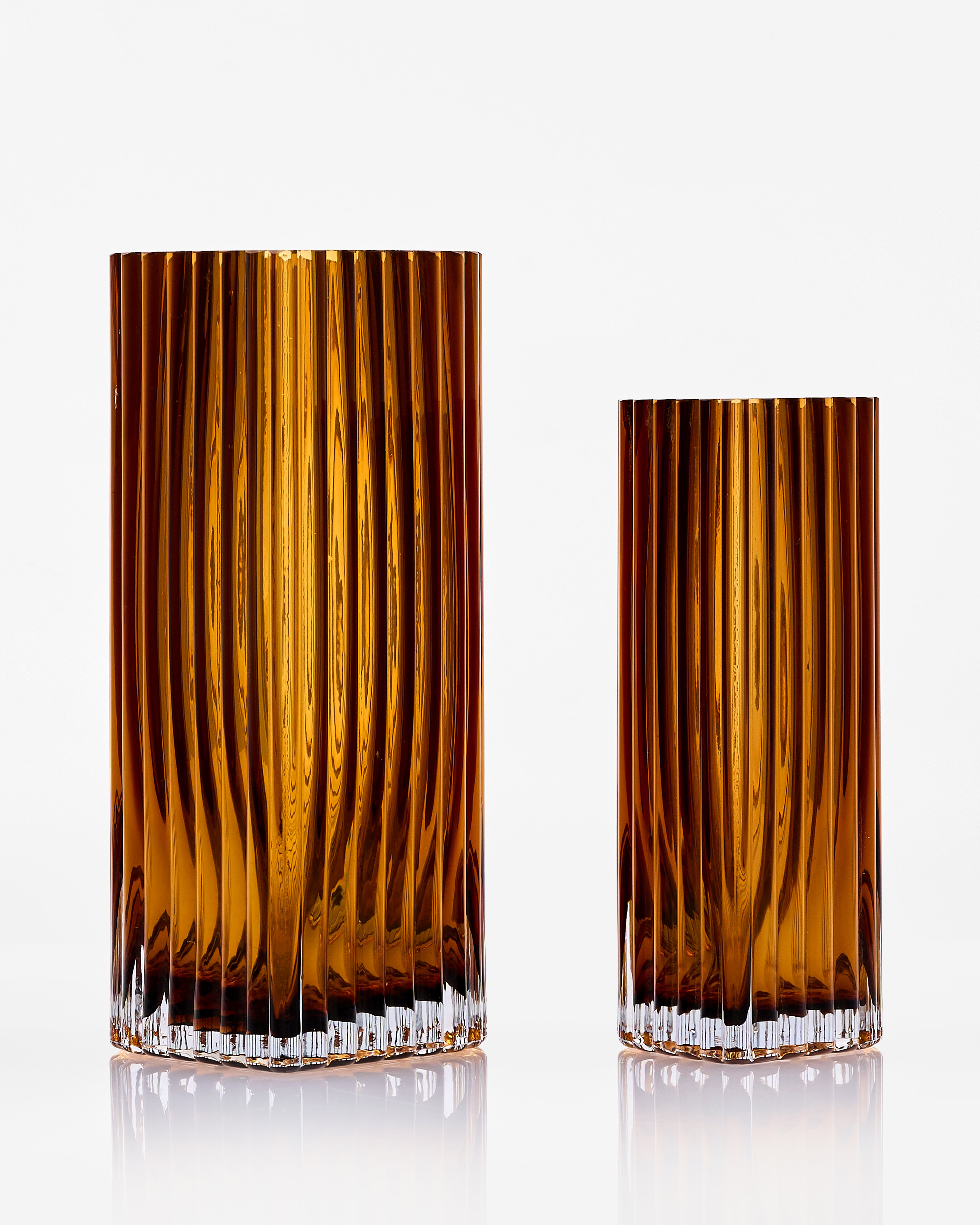 Two brown ribbed glass tumblers on a white background