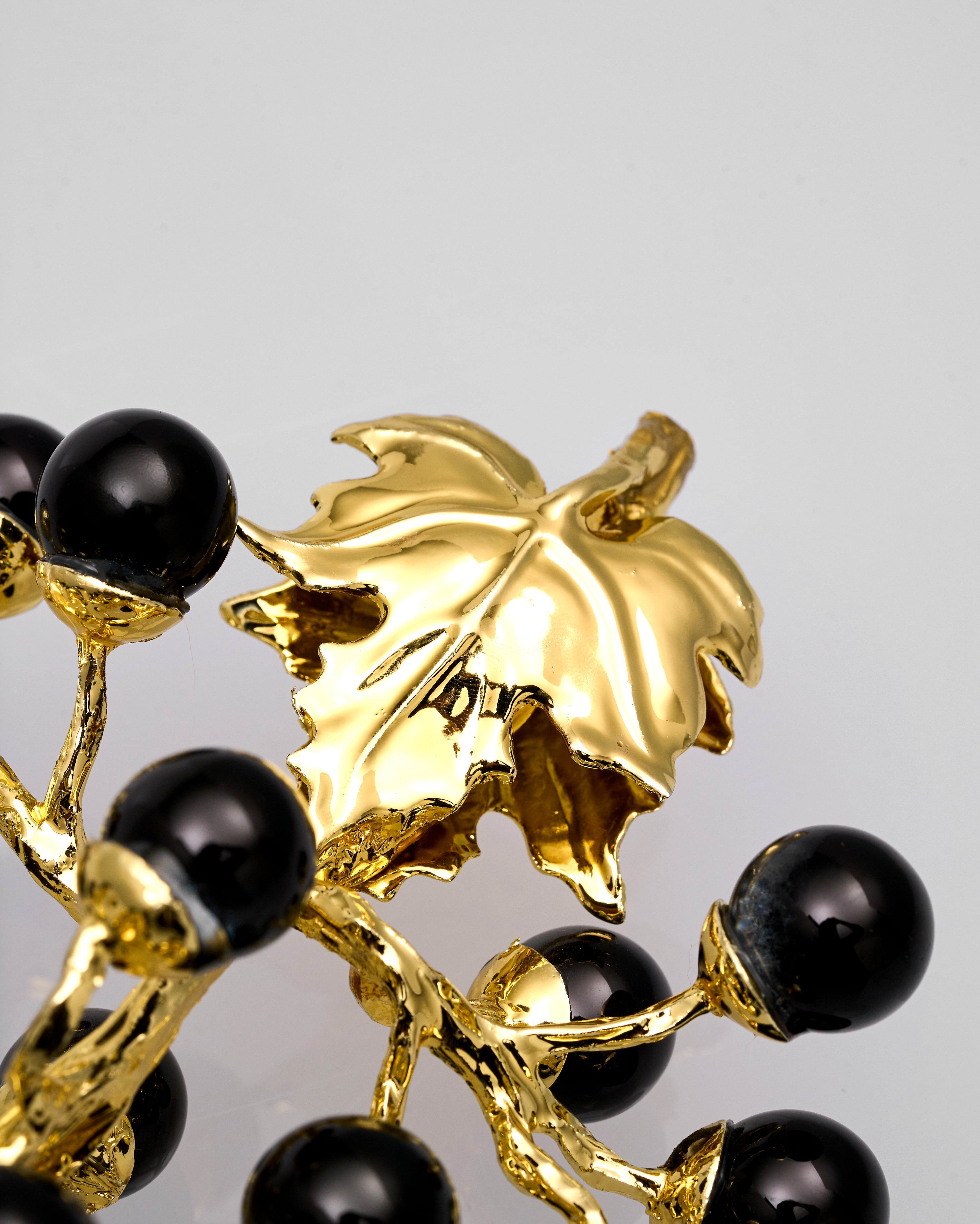 Gold metal leaf design with black beads on a gray background
