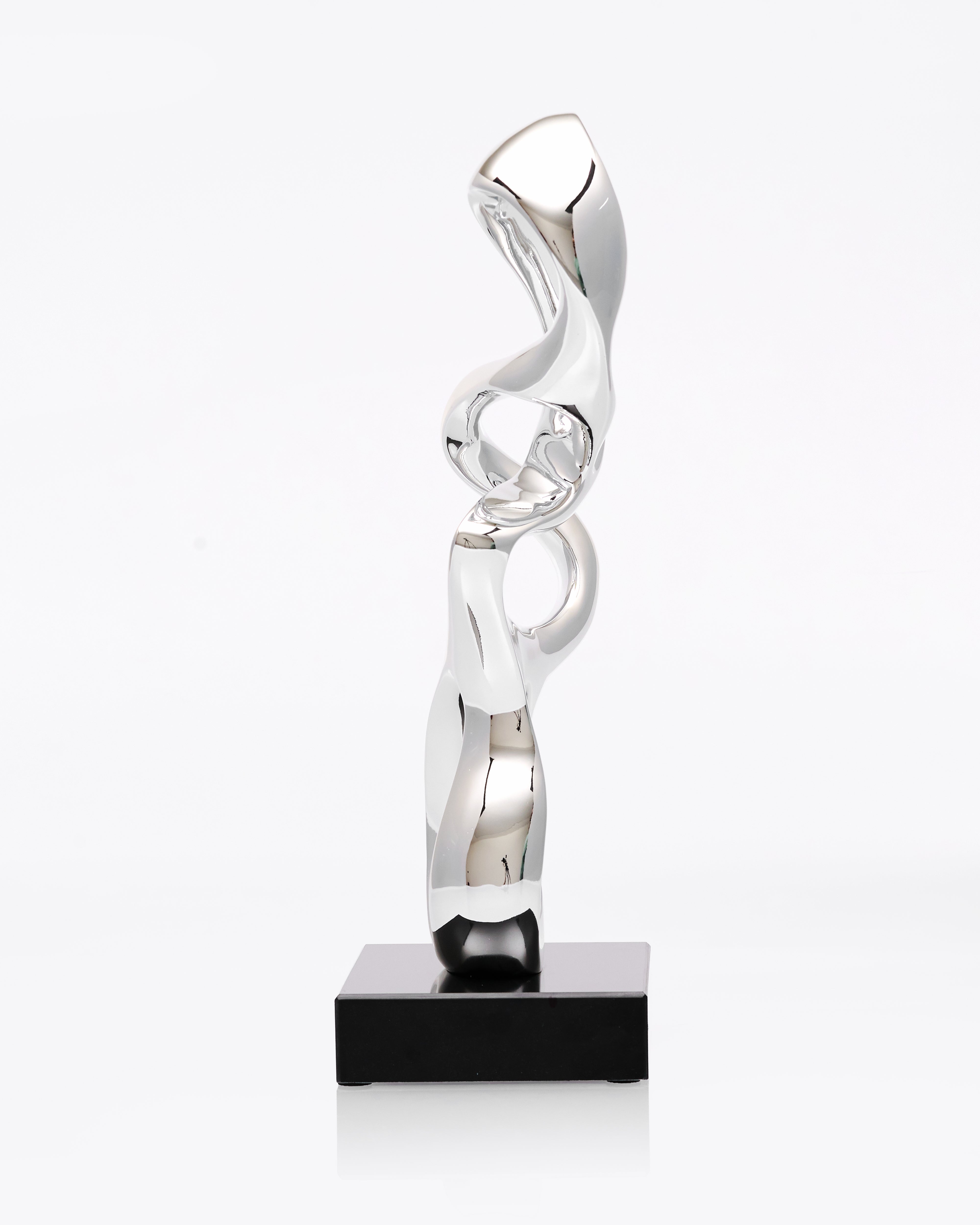 Silver abstract sculpture on a black base against a white background