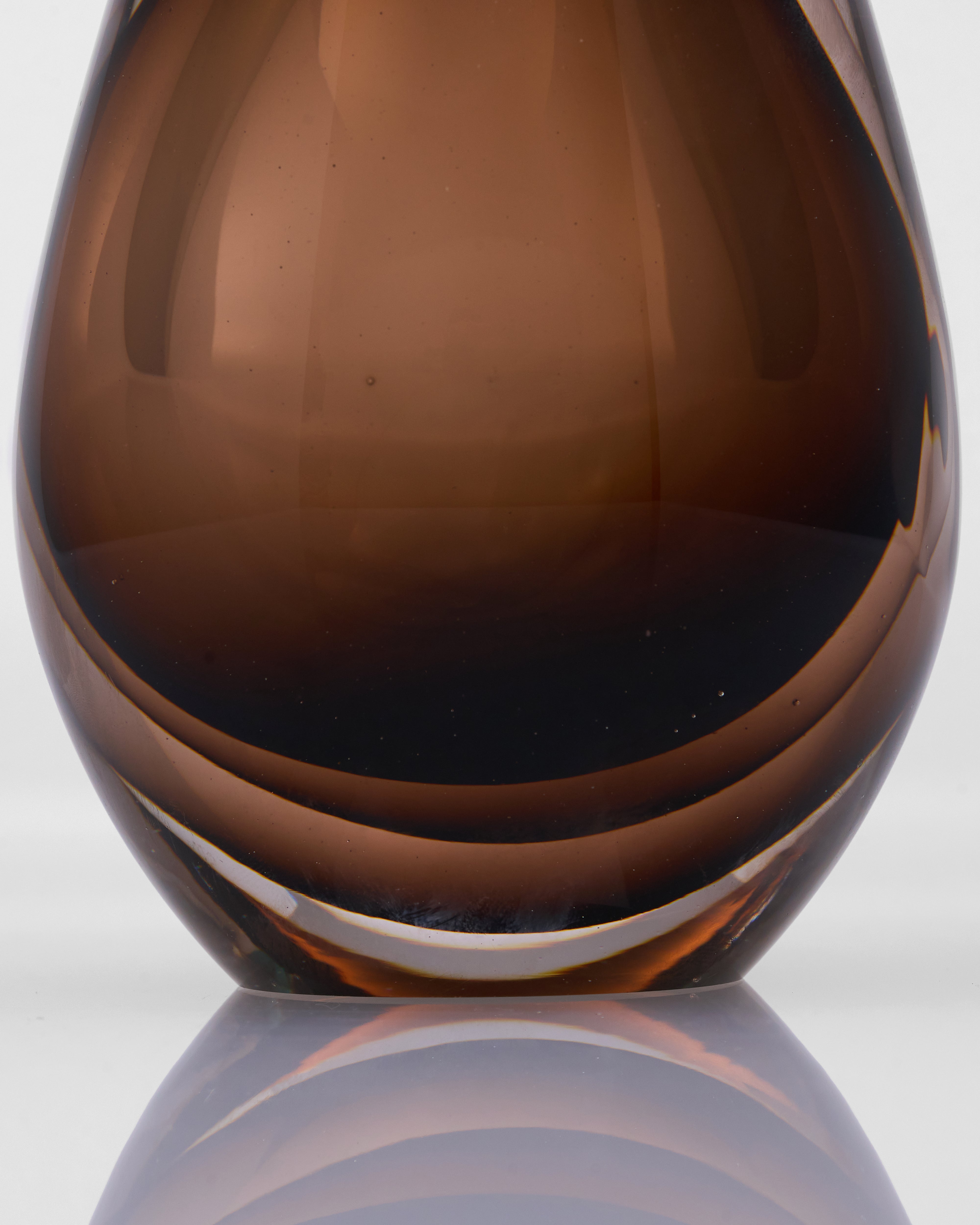 Brown glass vase on a reflective surface with a neutral background