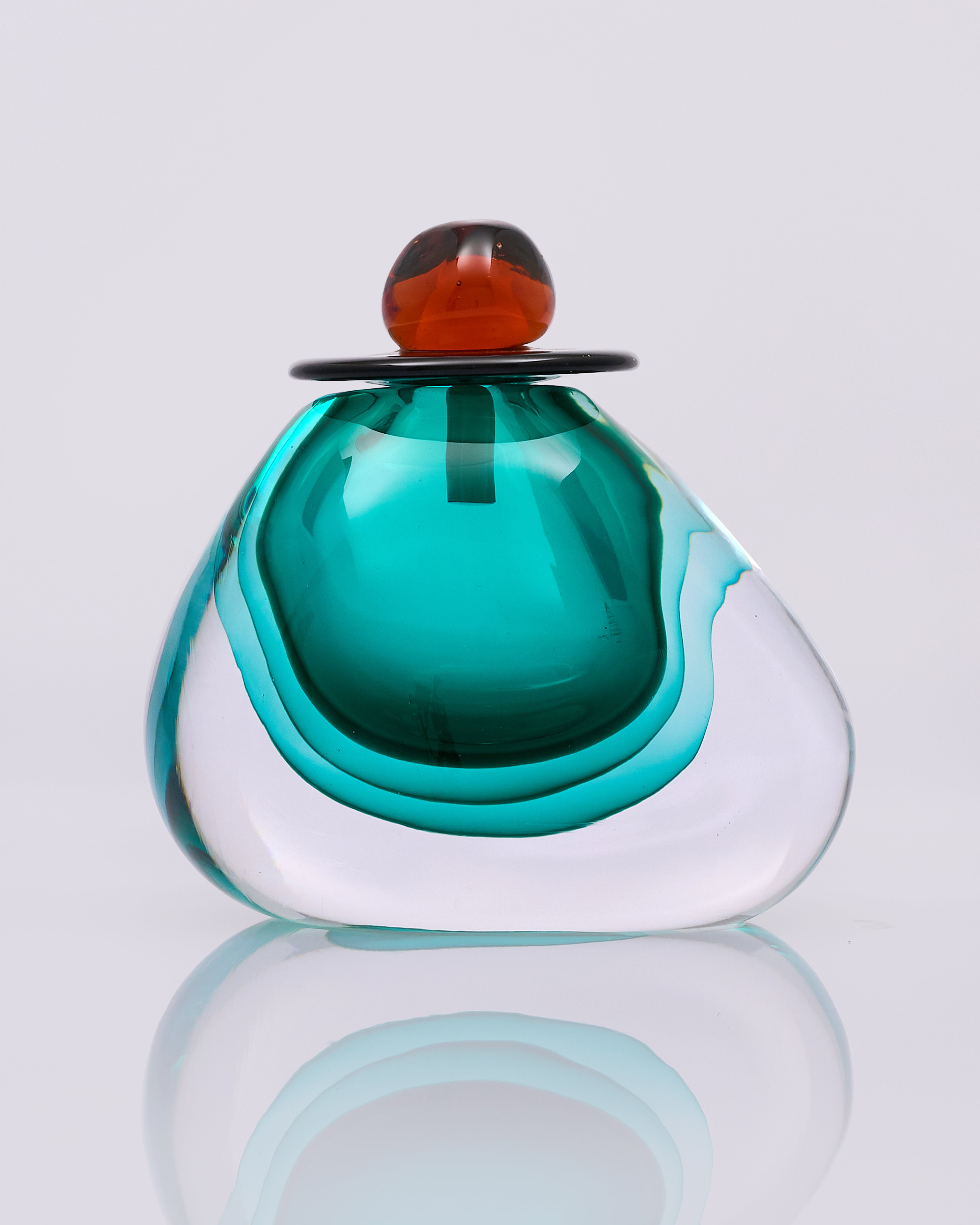 Glass sculpture with a gradient from green to white on a reflective surface