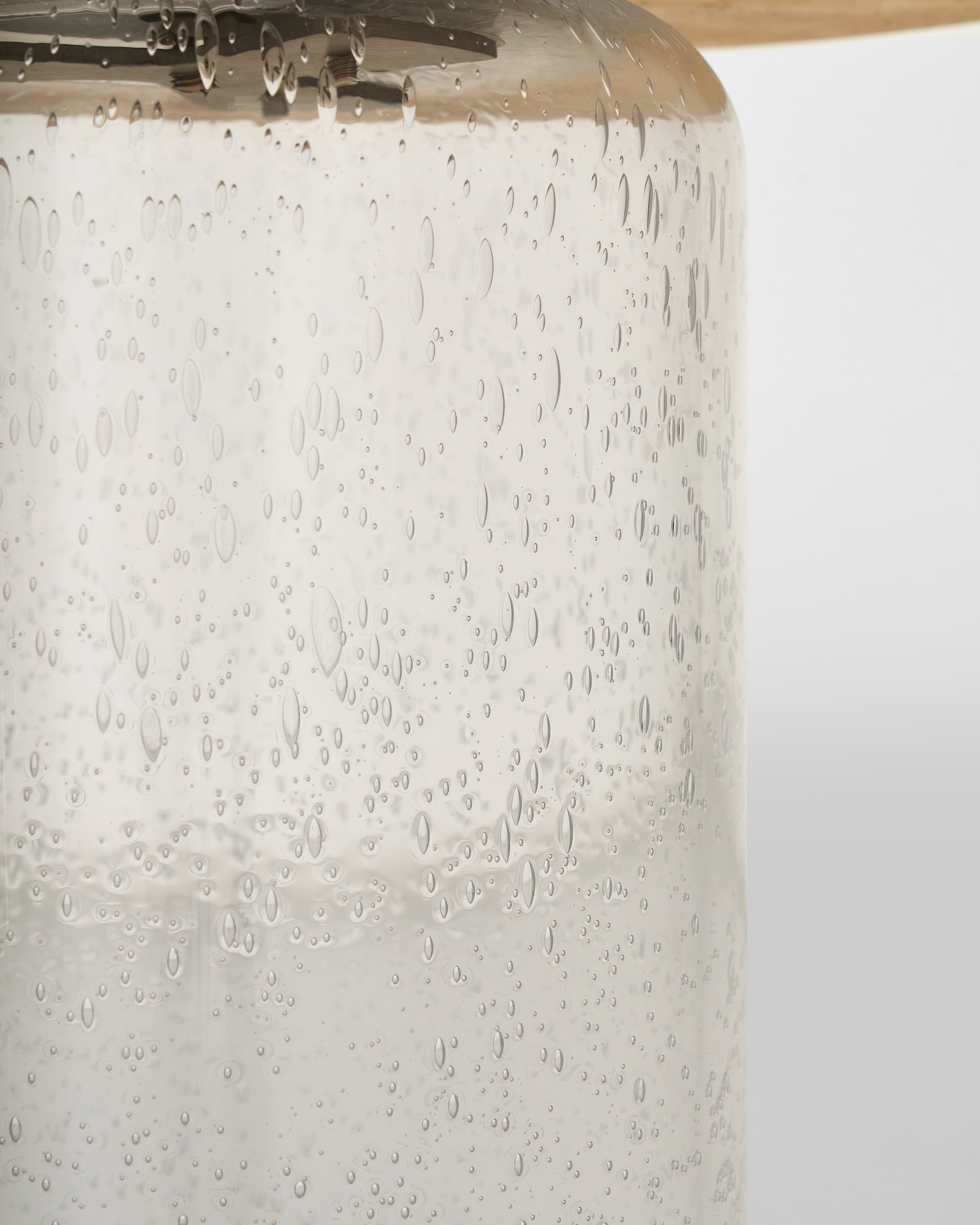 Close-up of a textured glass vase with water droplets on a white background