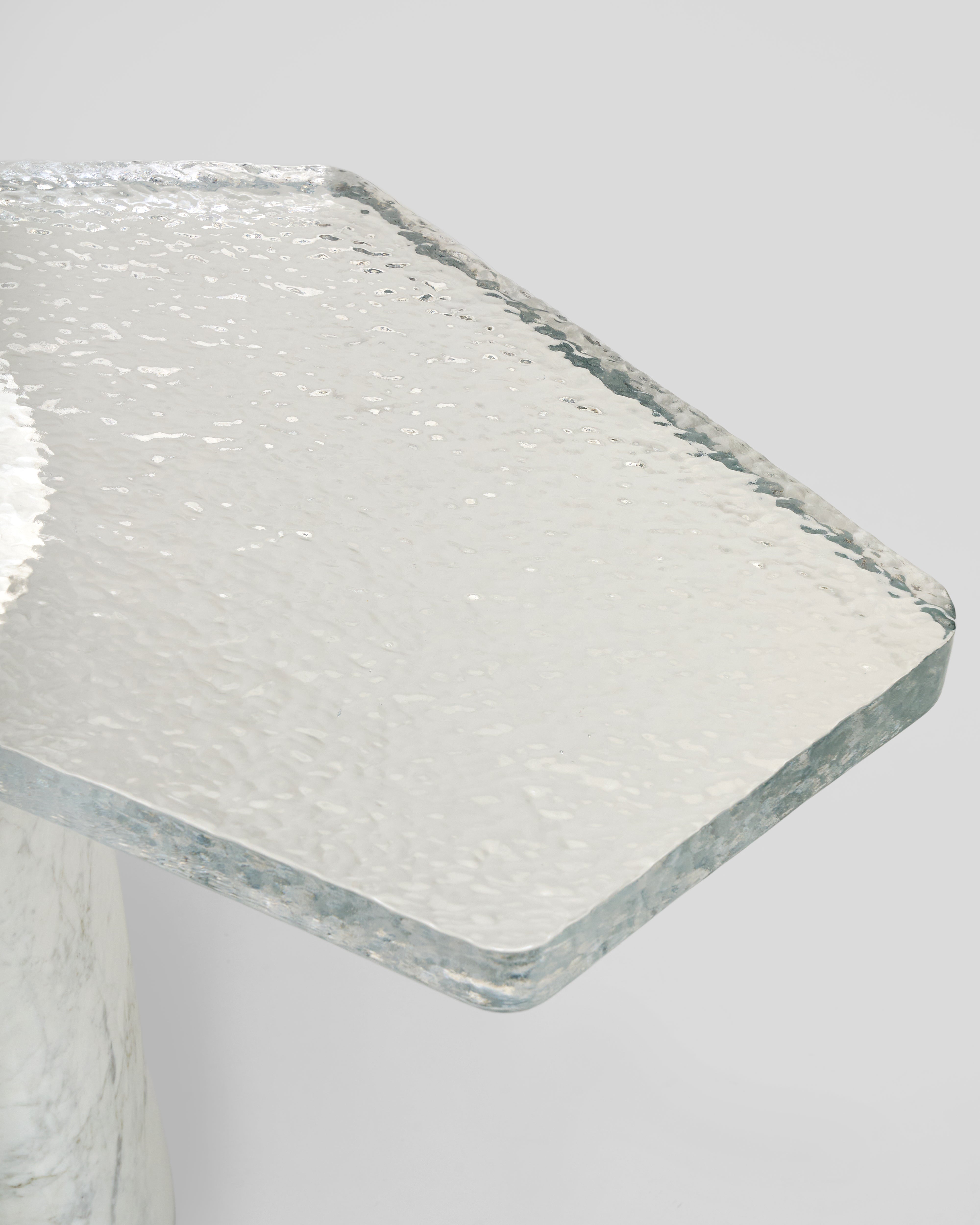 Clear glass tabletop of side table marble with a textured surface on a light gray background