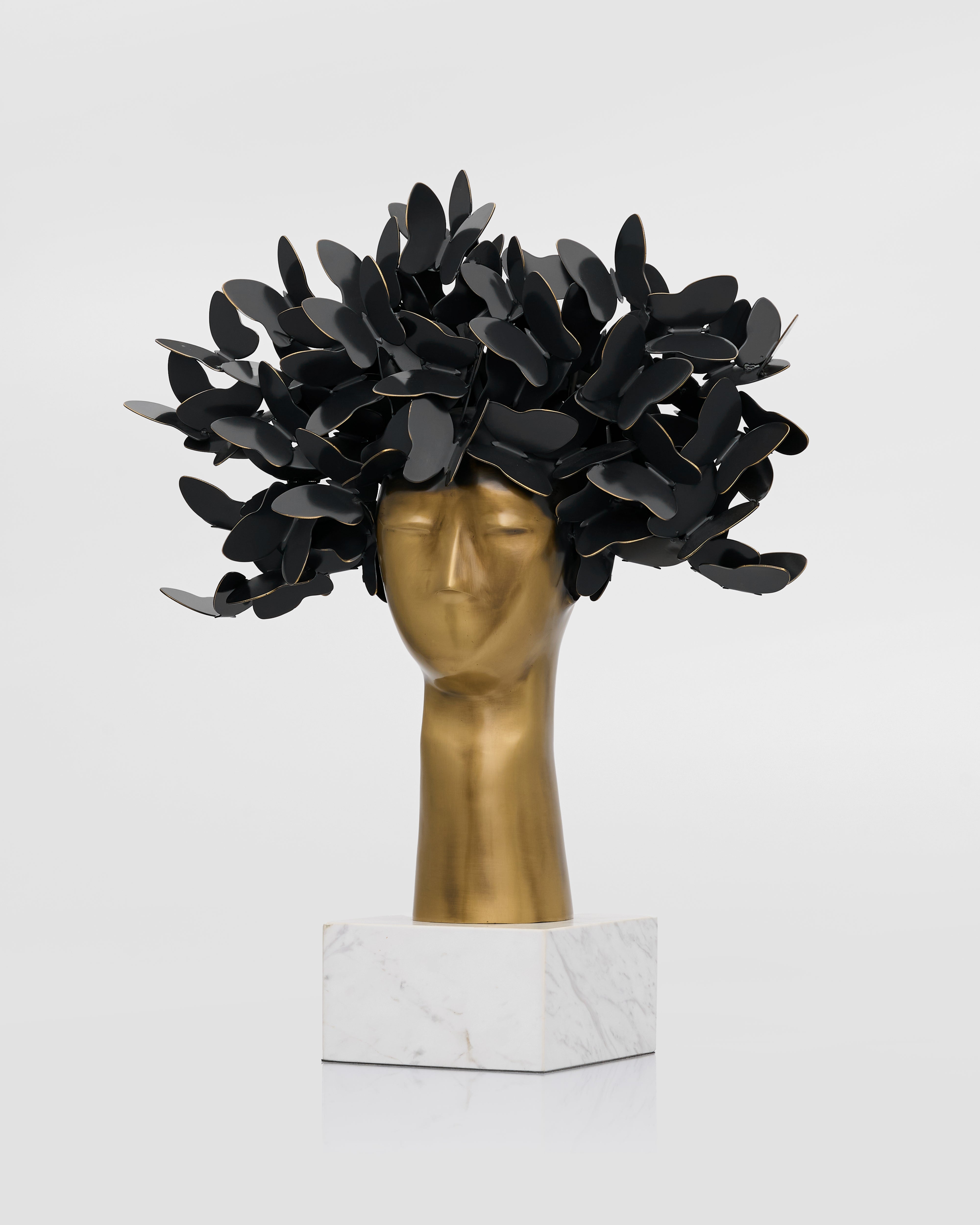 Black leaf-like structure on a gold head sculpture with a white background