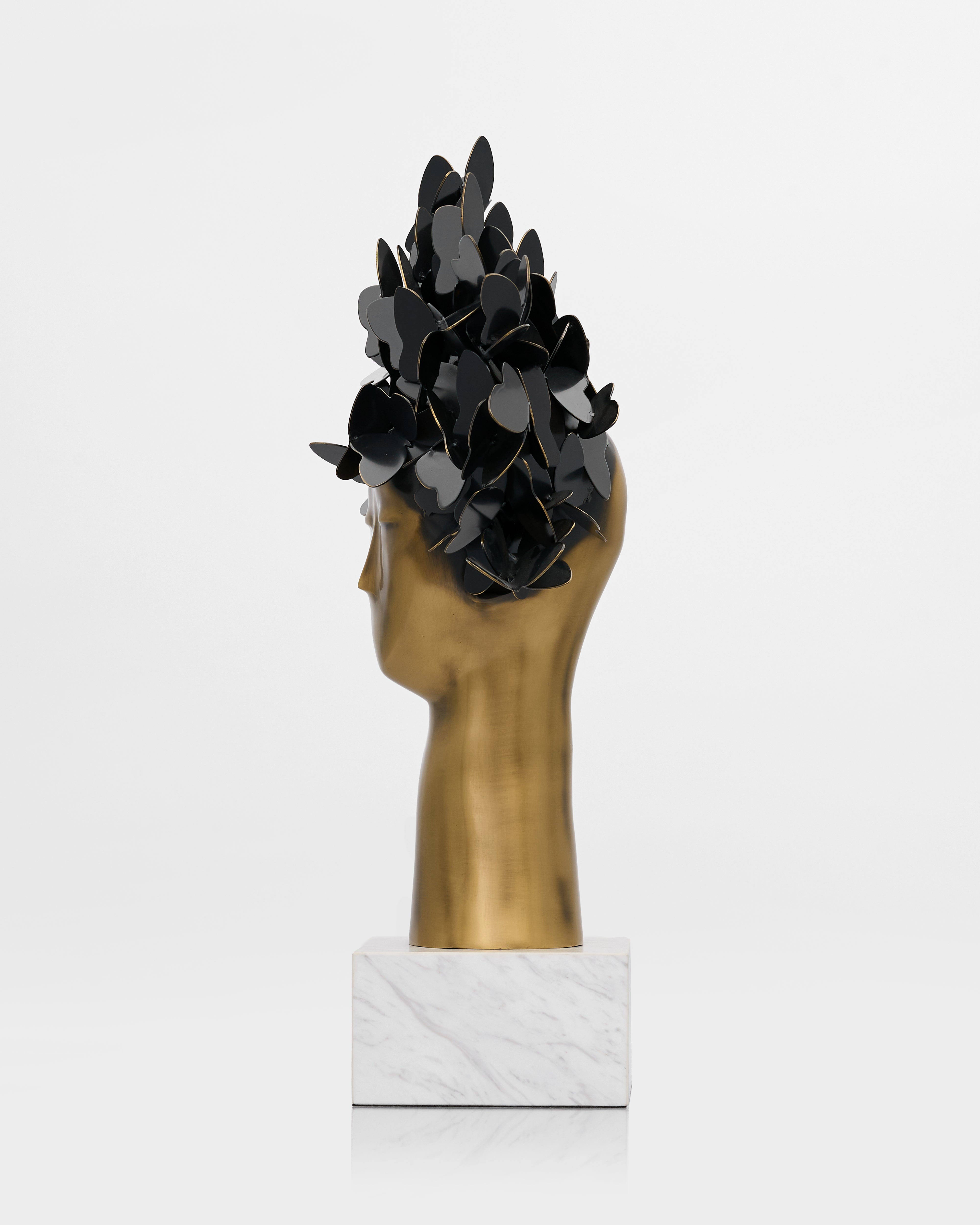Decorative headpiece with black leaves on a gold head and marble base against a white background
