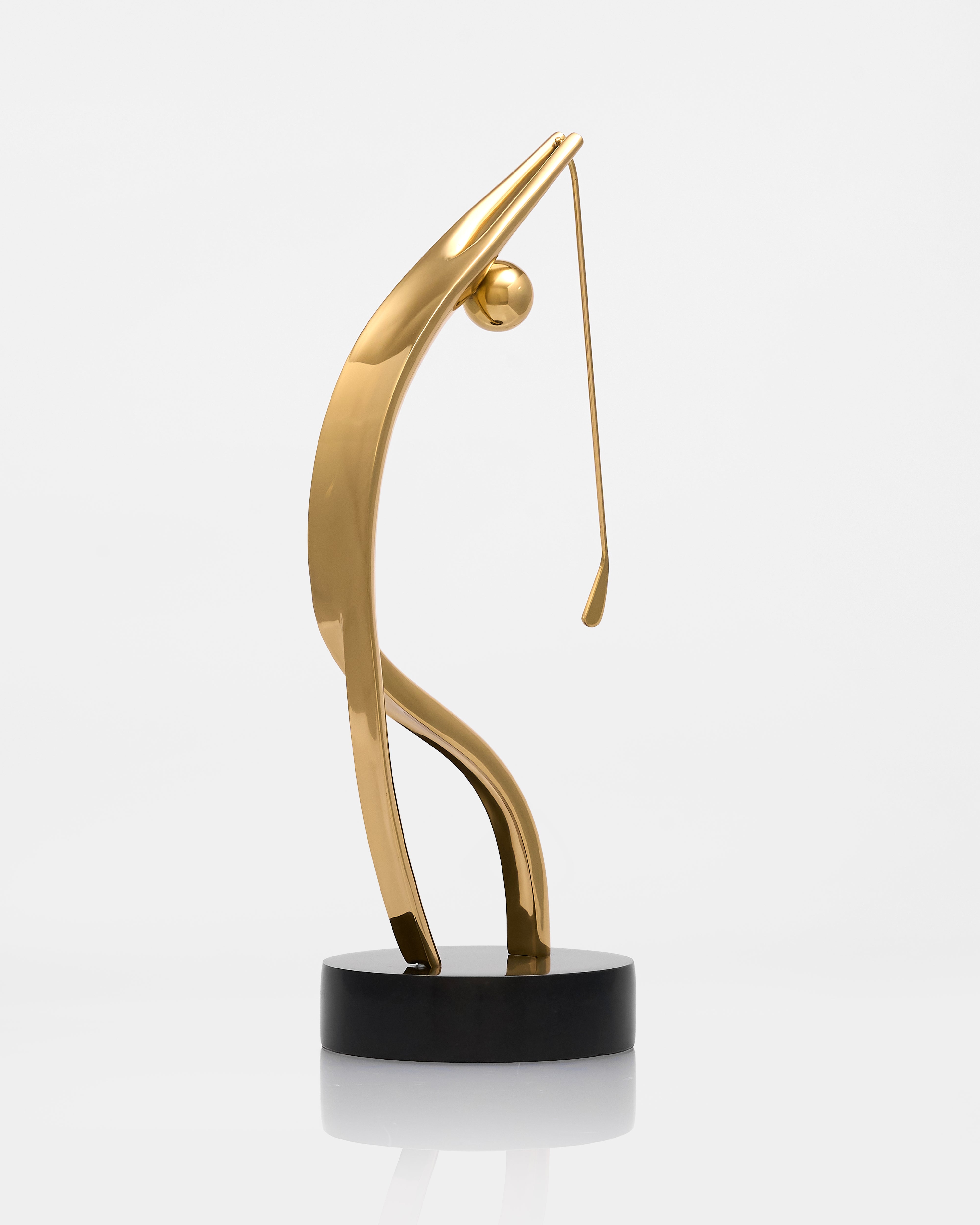 Gold sculpture on a black base against a white background