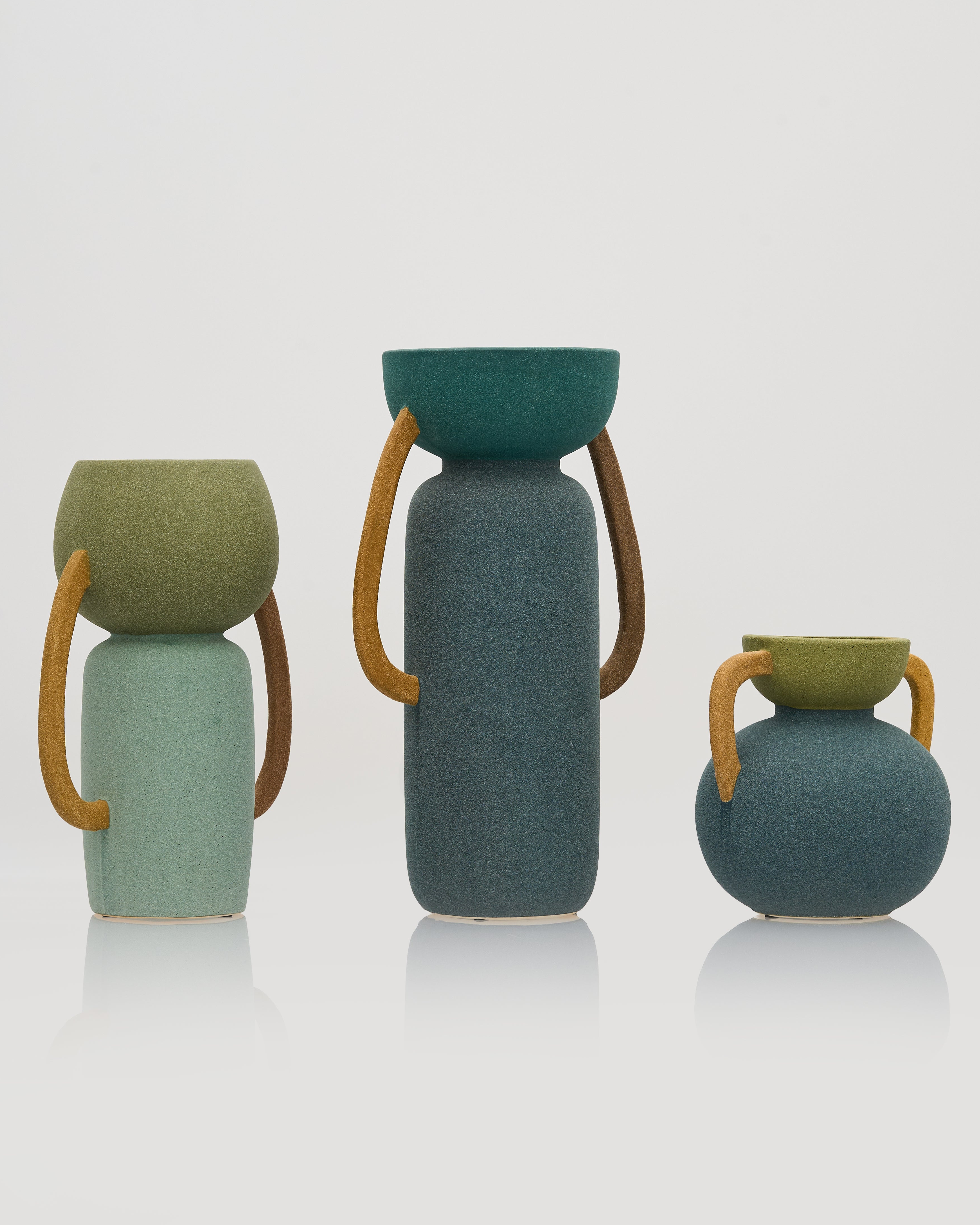 Set of three ceramic vases with handles on a white background