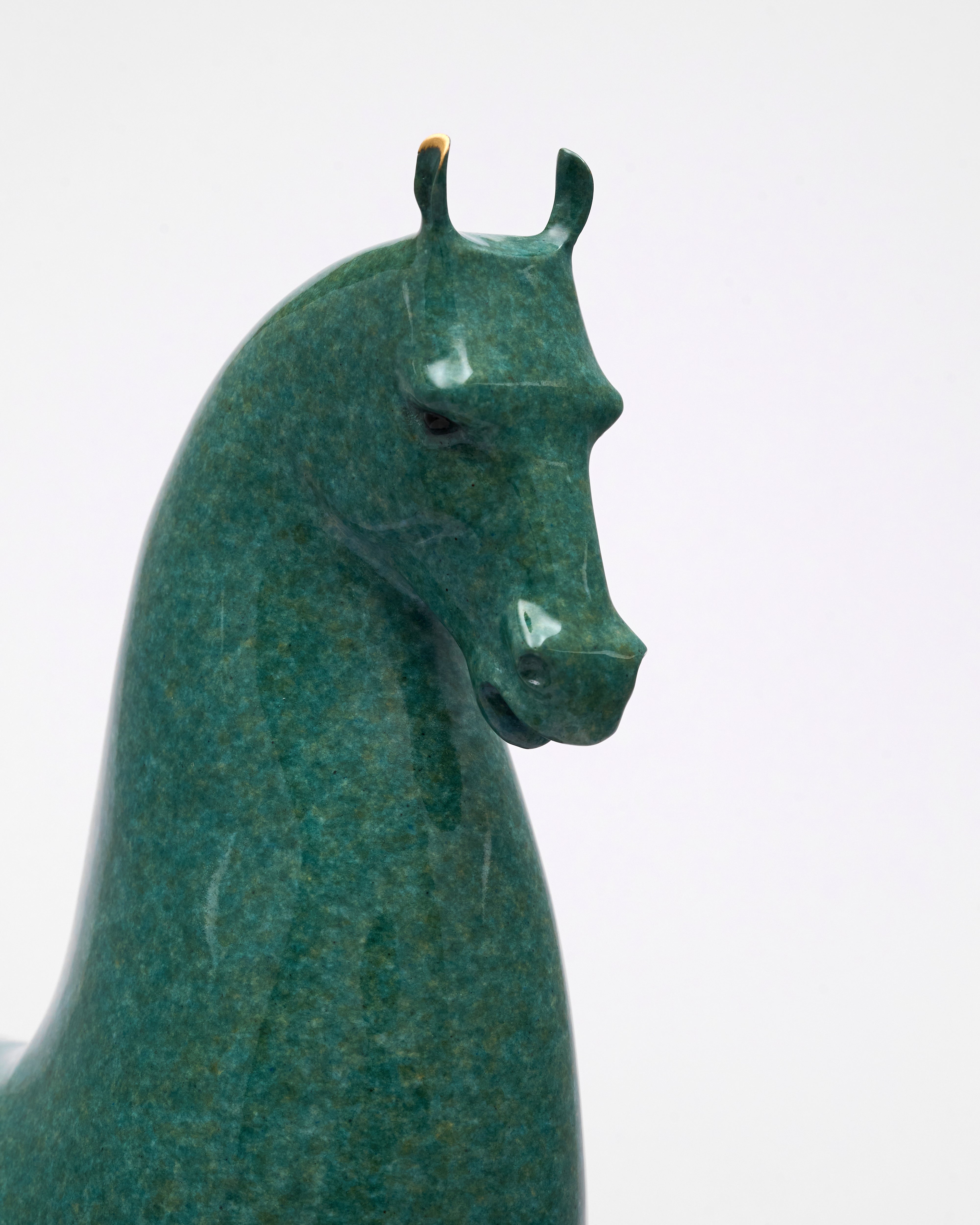 Green stone sculpture of a horse head on a white background