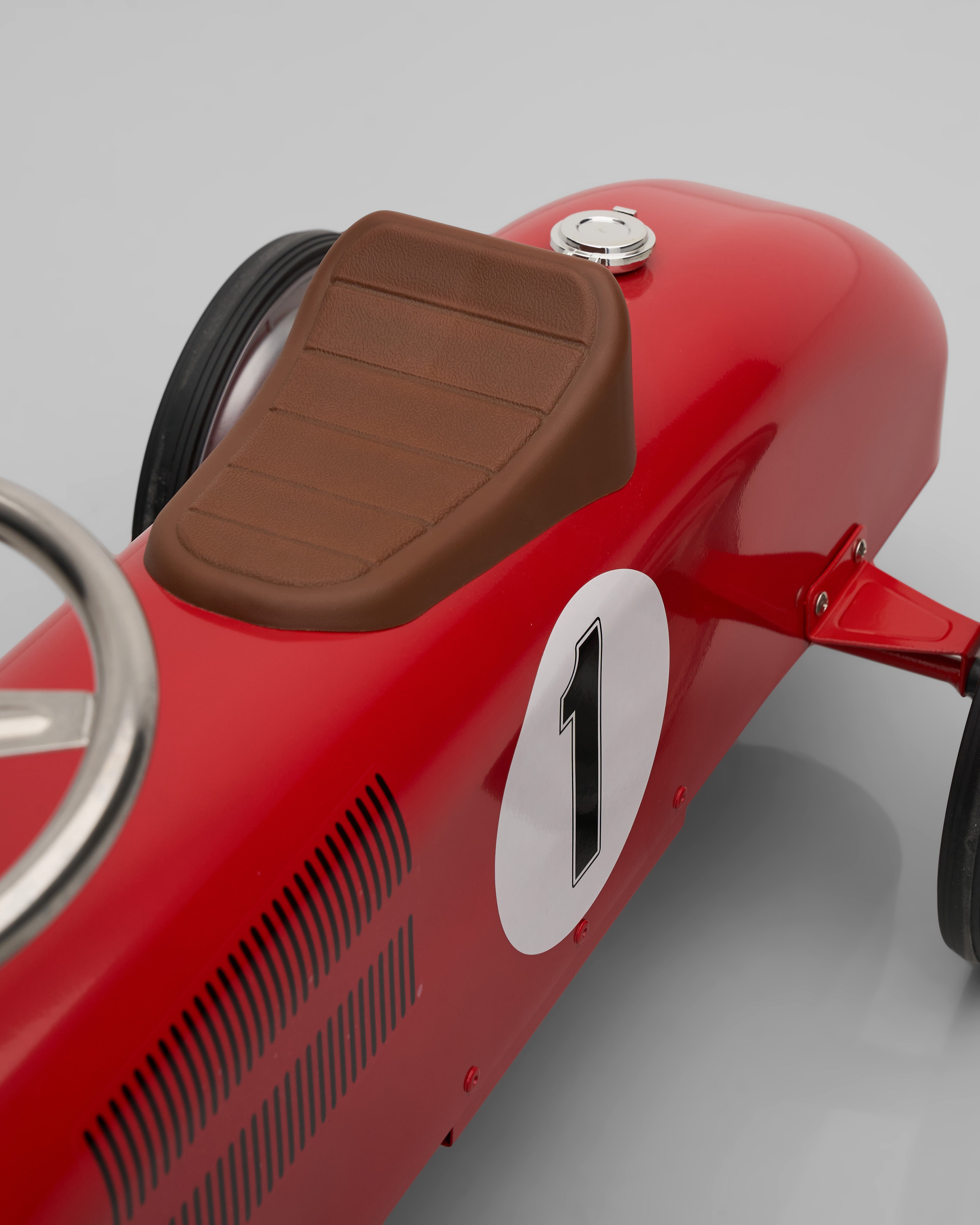 Red toy vintage car decor with a brown seat and number 1 on a gray background