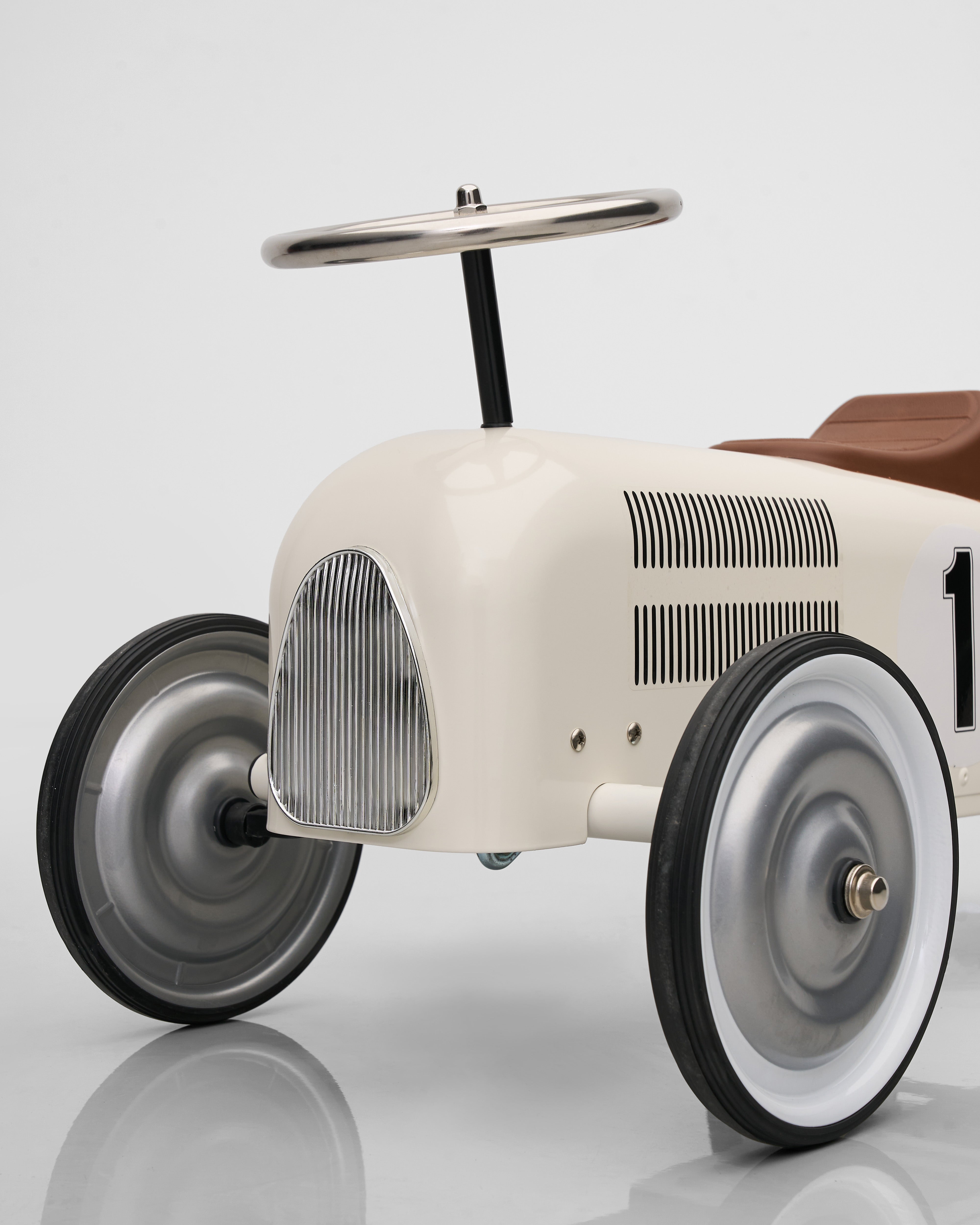 Vintage-style toy car with a white body and brown roof on a reflective surface.