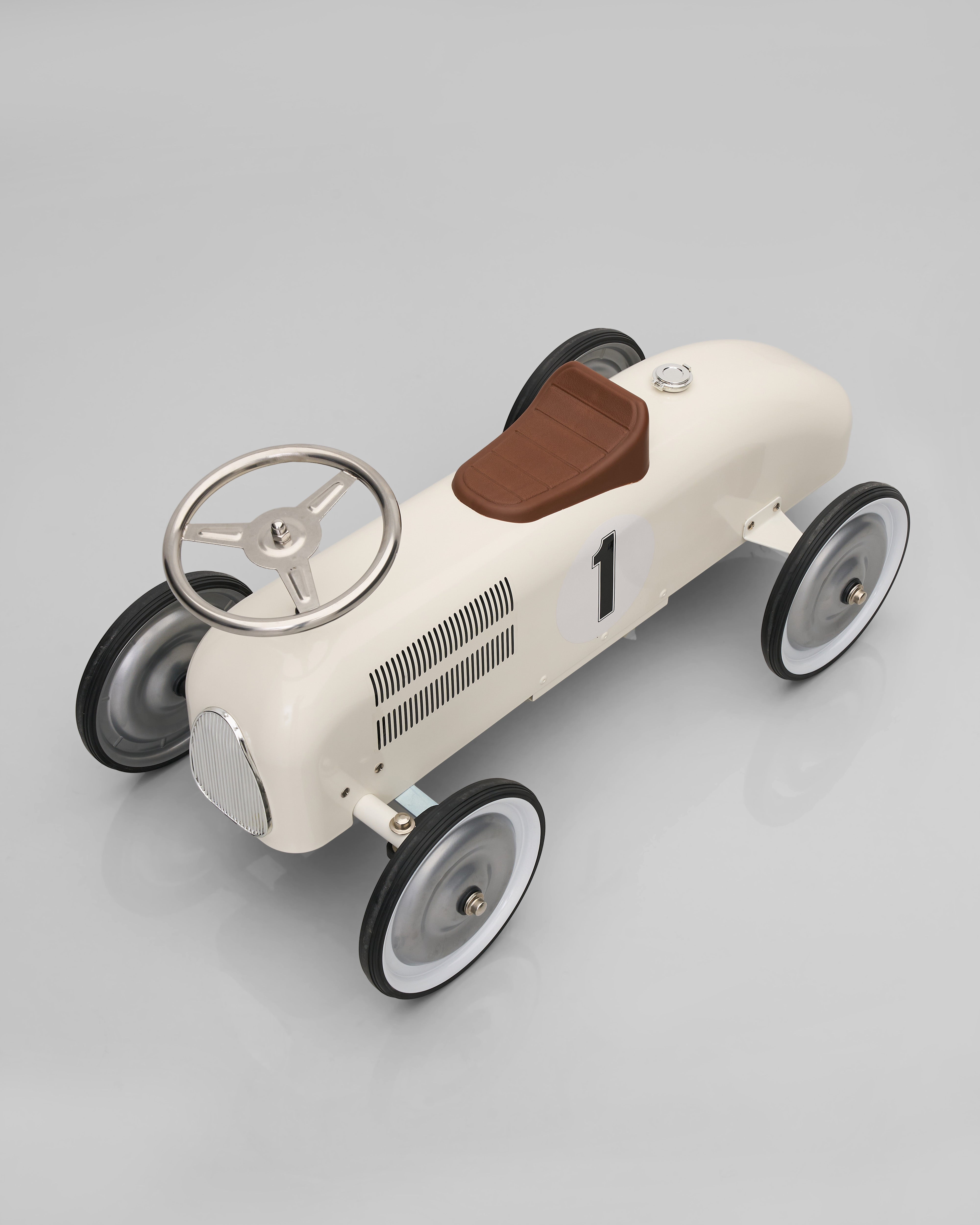 Vintage-style toy car with a white body, brown seat, and black wheels on a gray background