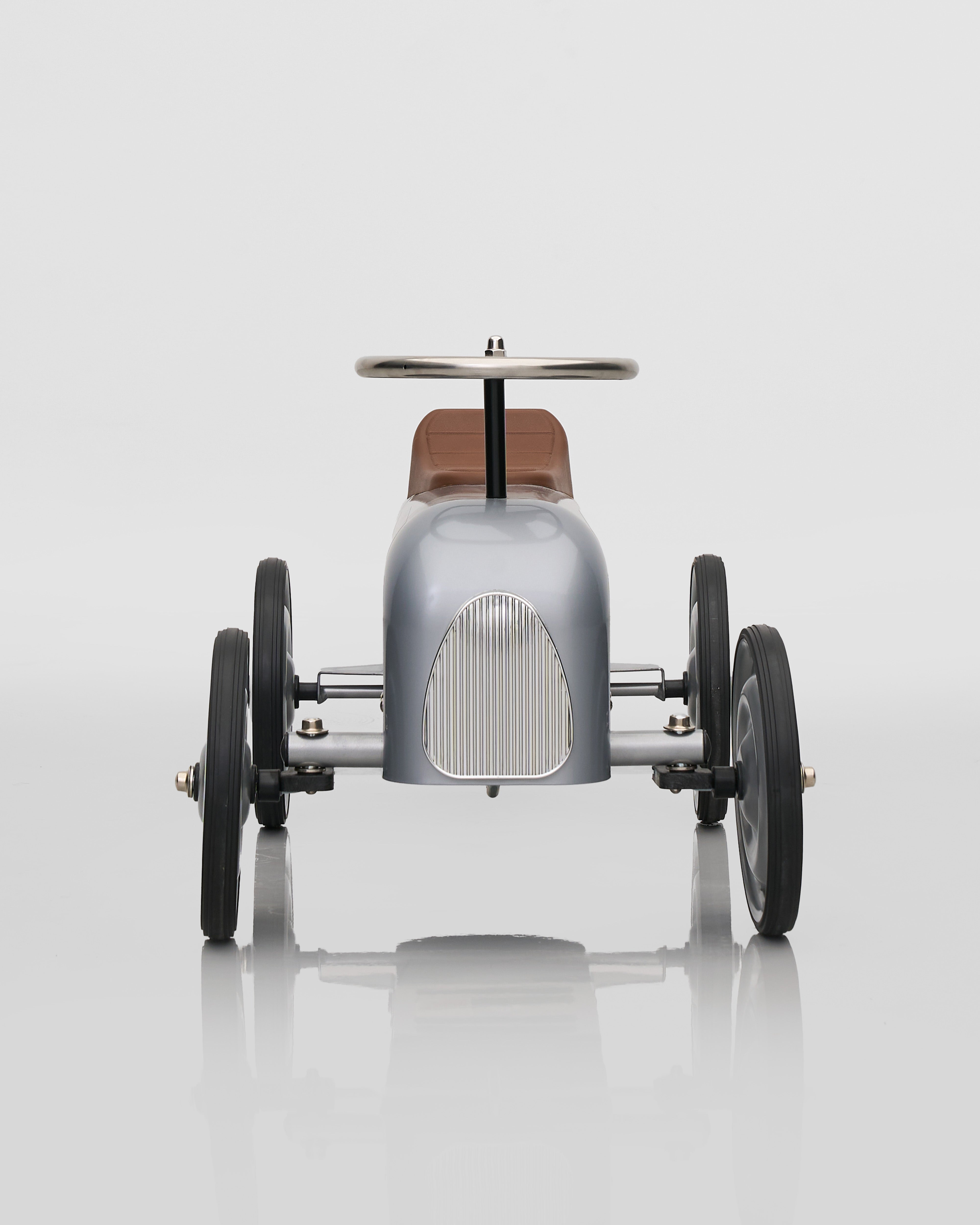 Vintage-style toy car on a reflective surface with a white background