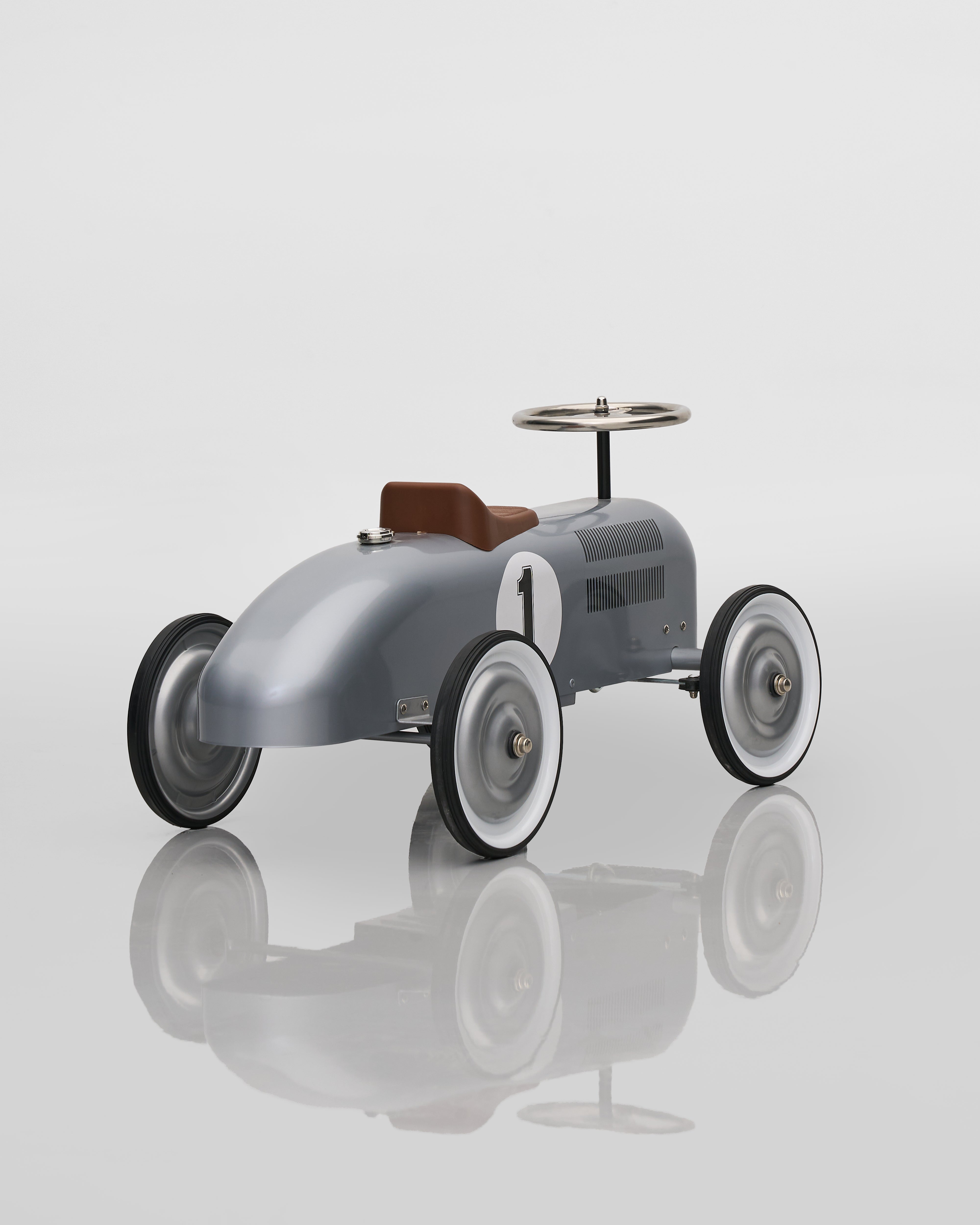 Vintage-style toy car on a reflective surface with a light gray background