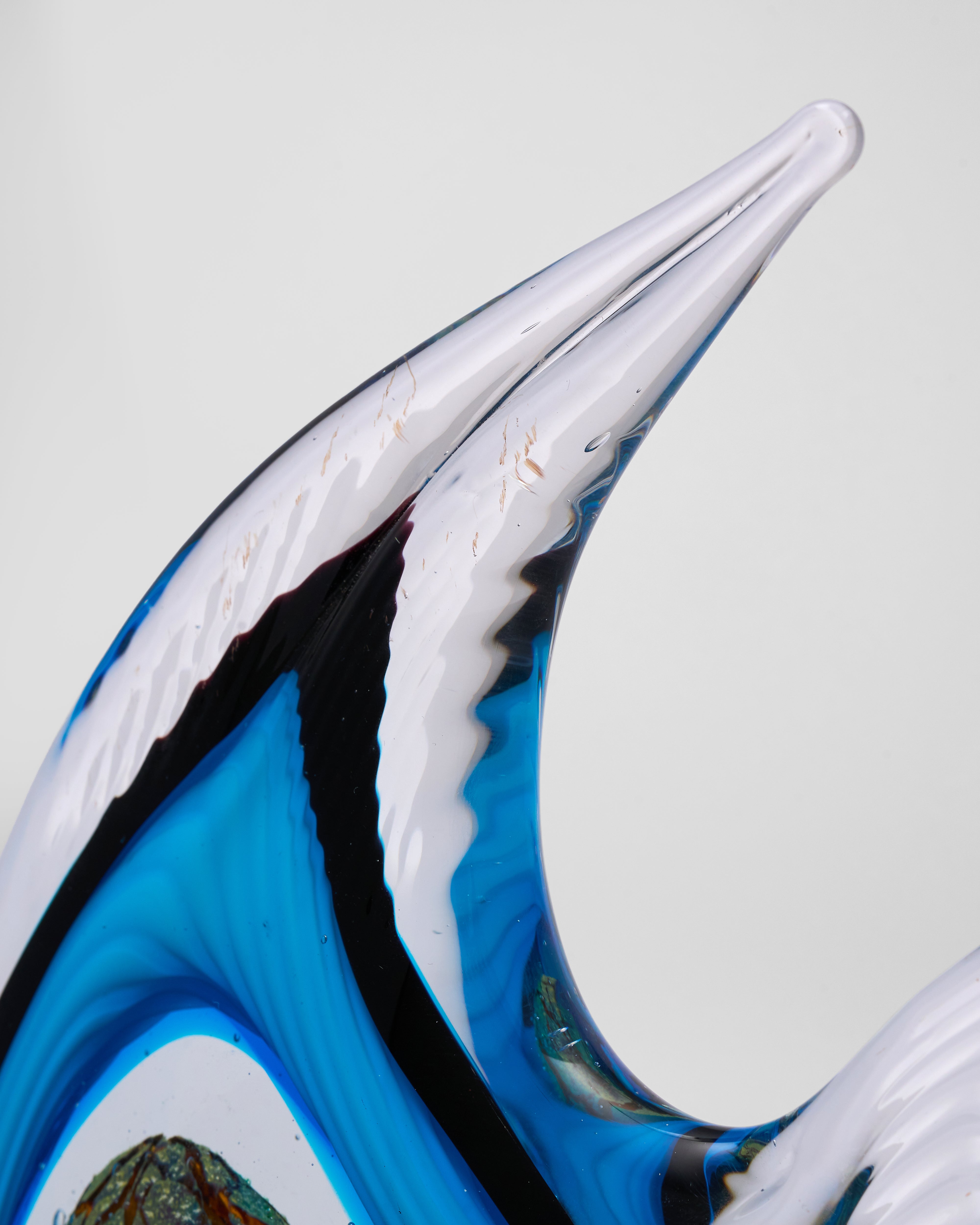 Glass sculpture of a wave with blue and white colors on a light gray background