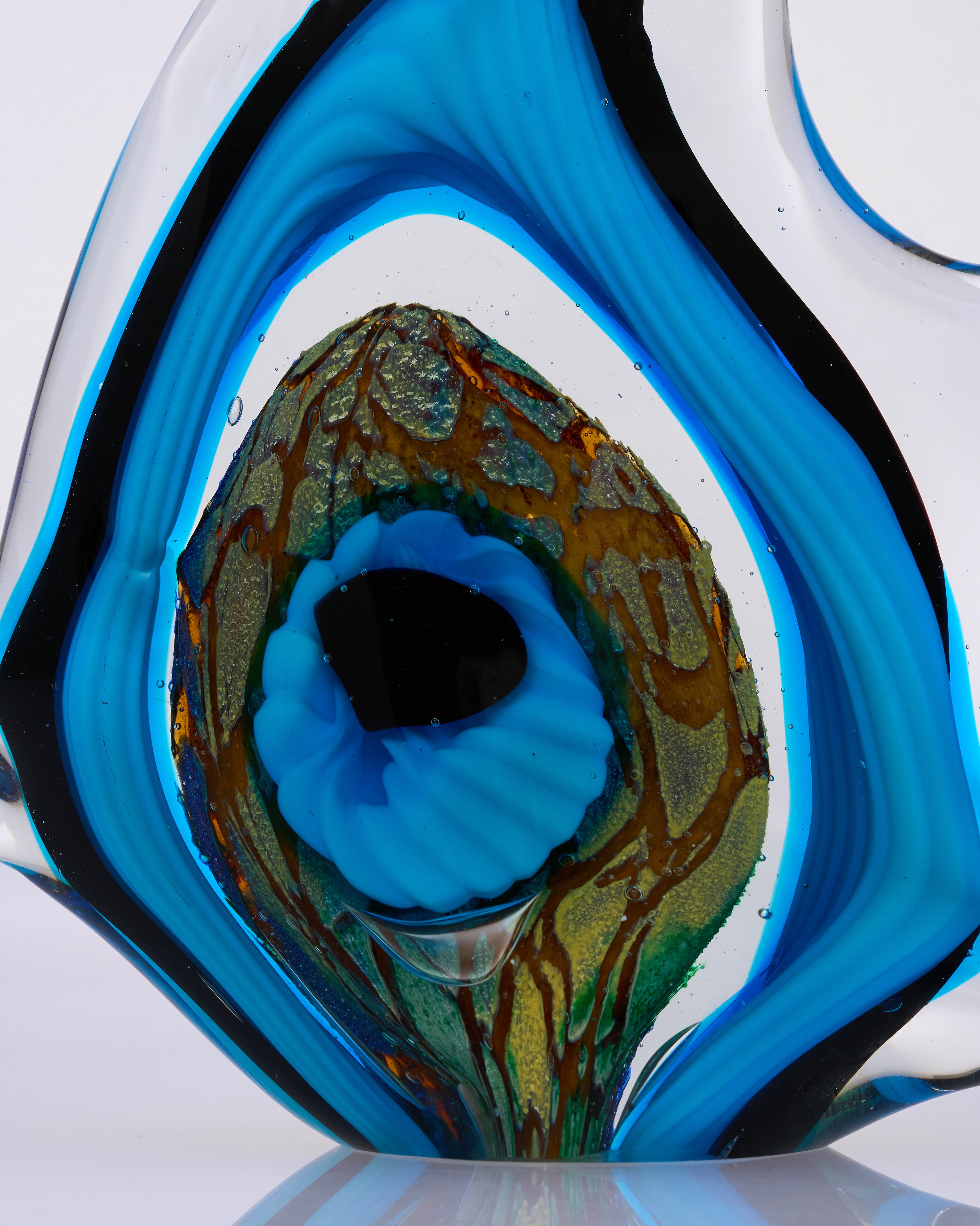 Close-up of a glass sculpture with blue and green colors on a white background