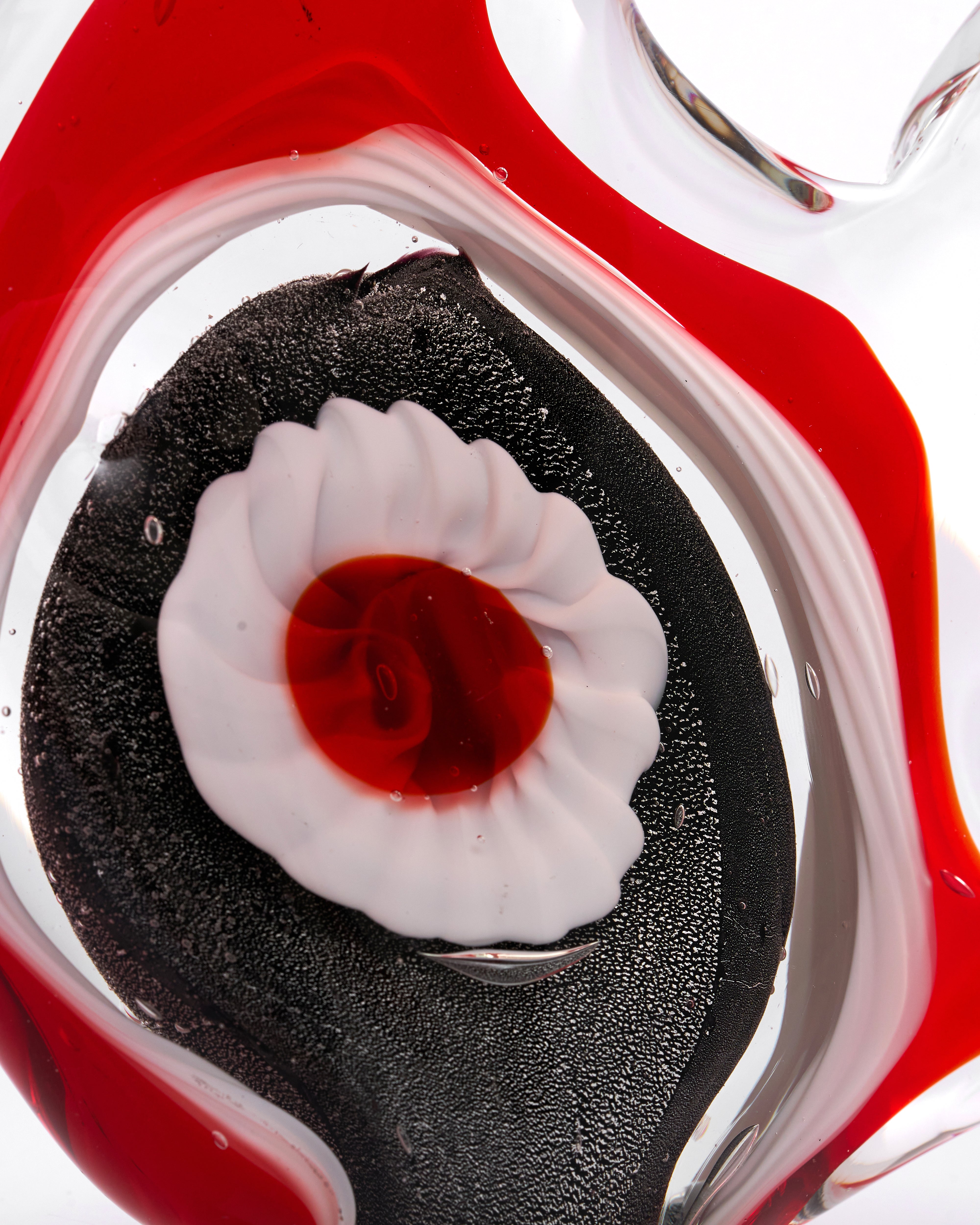 Close-up of a white and red center in a clear Vynta Crystal Glass Red Fish Decor with red liquid.