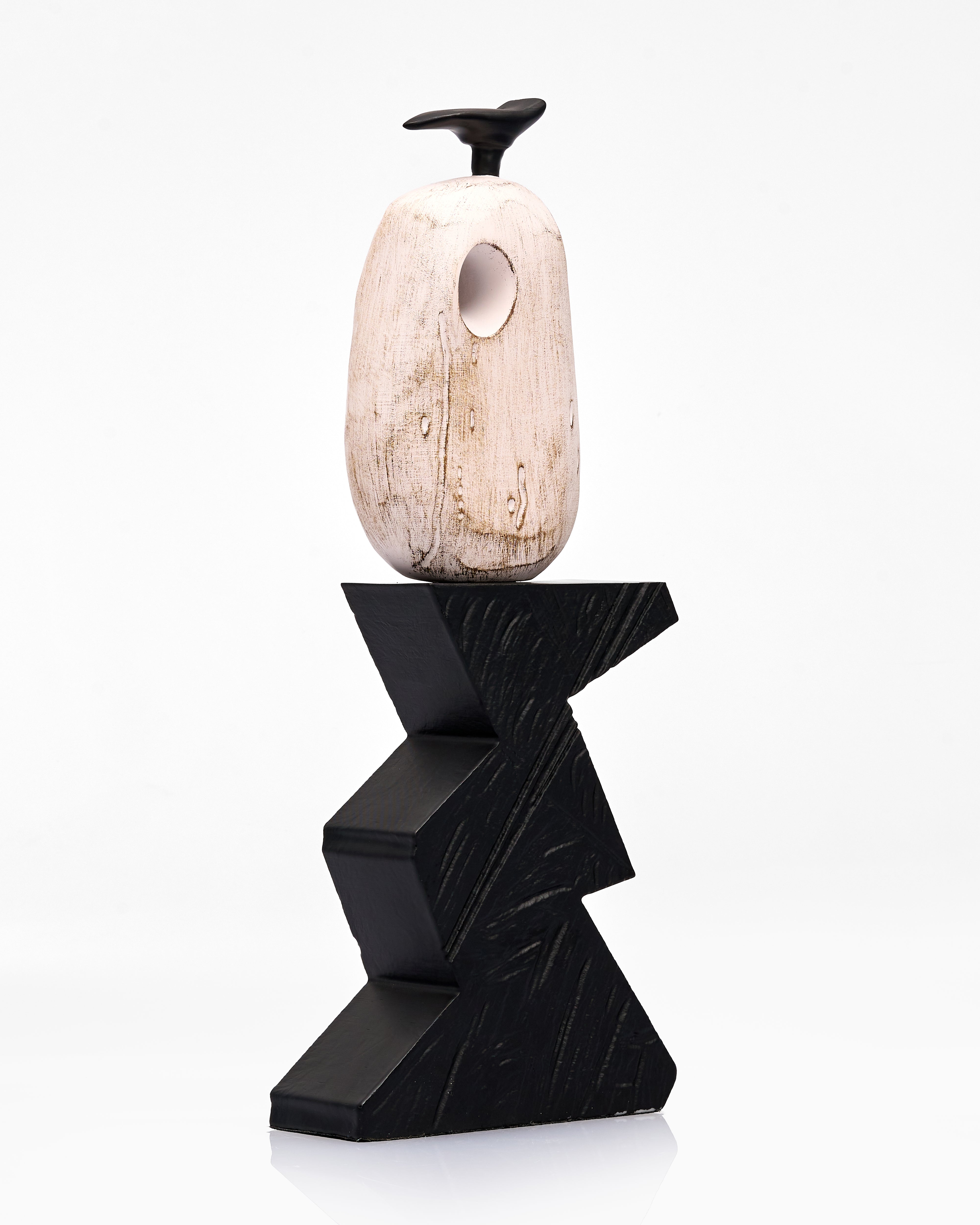 Decorative object with a black zigzag base and a beige stone-like top on a white background