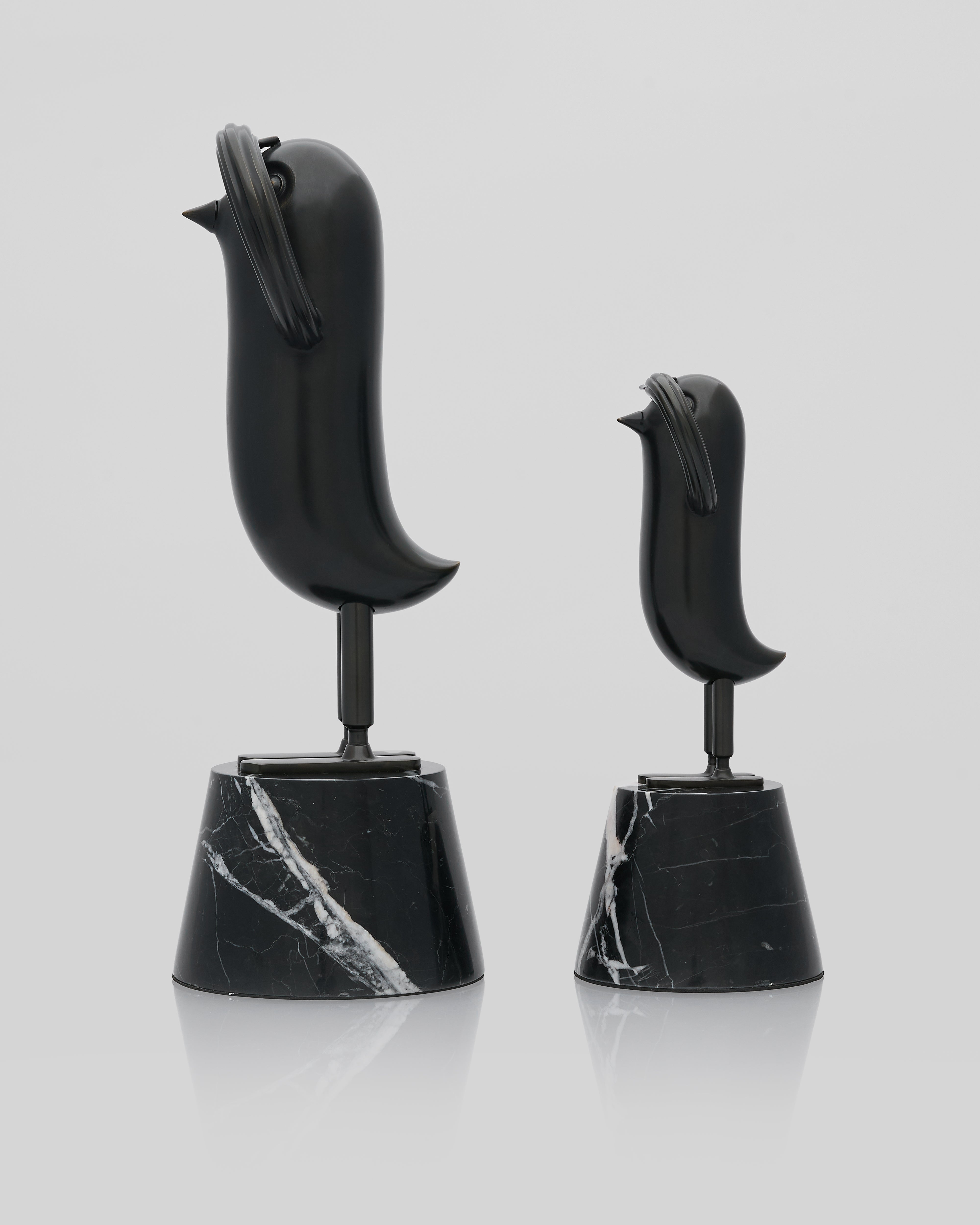 Two black marble bird salute figurines on a light gray background