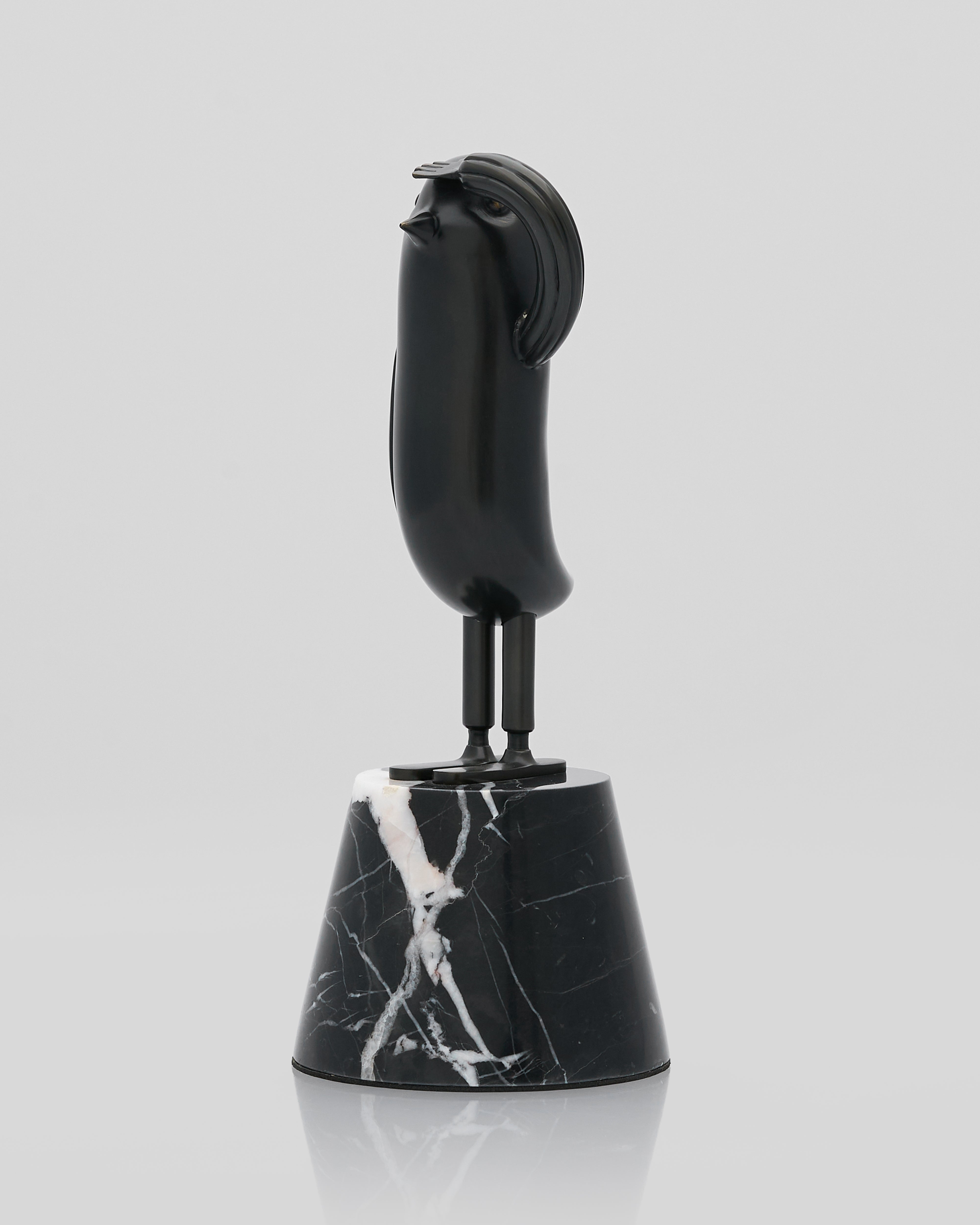 Black marble bell with a bird-like top on a light gray background