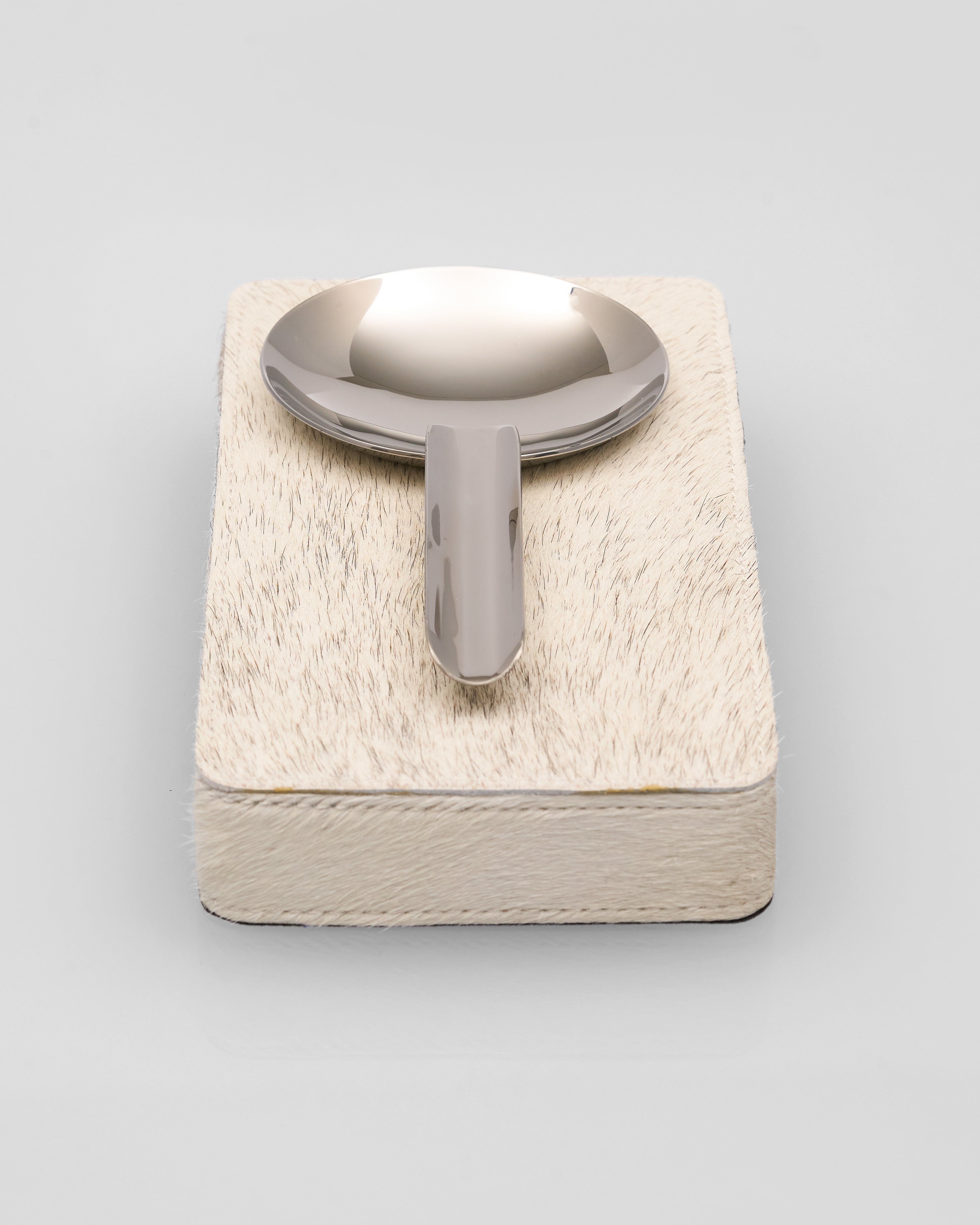 Rectangular ceramic dish with textured surface and metal spoon on a light gray background