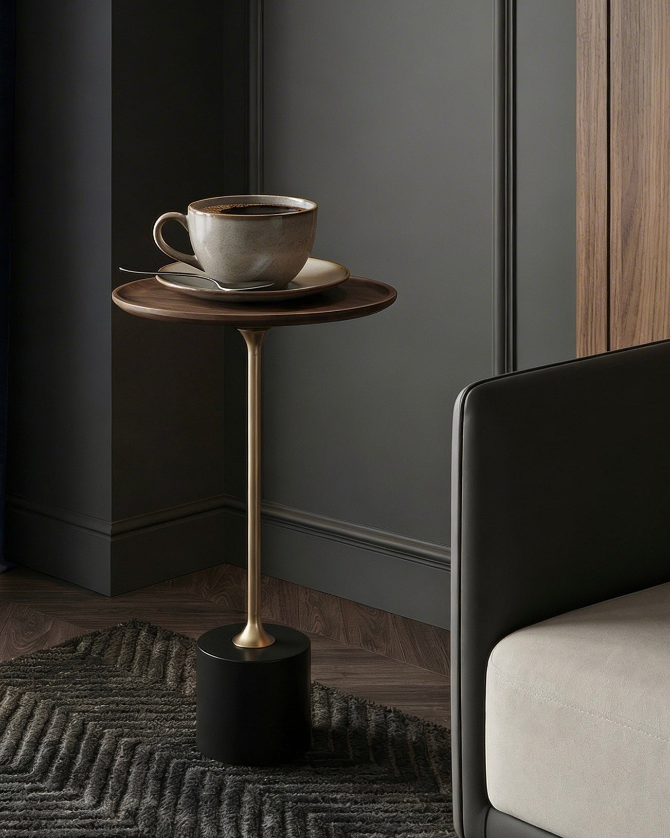 Small round table with a cup on it next to a modern chair against a dark wall.