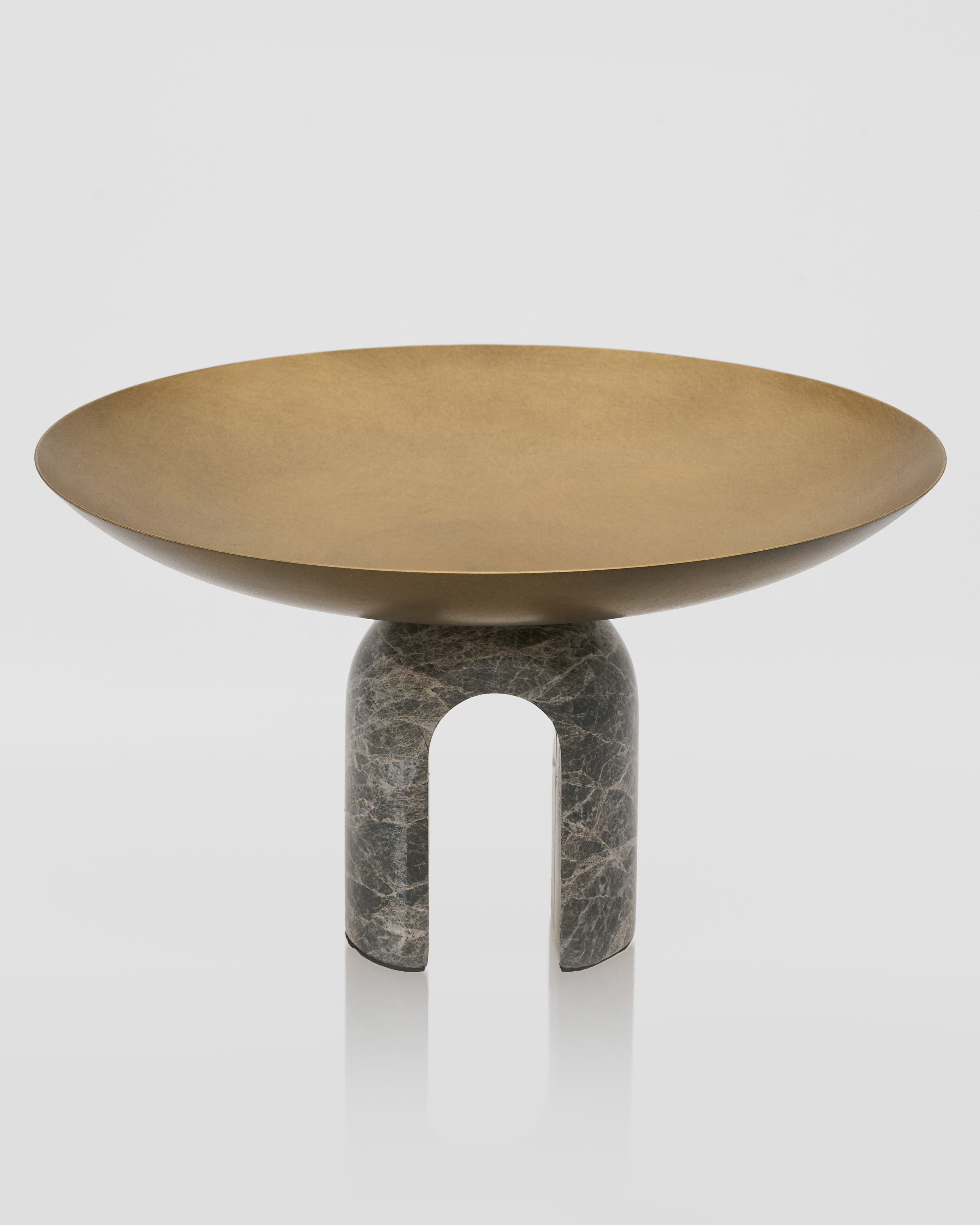 Modern table with a bronze top and marble base on a white background