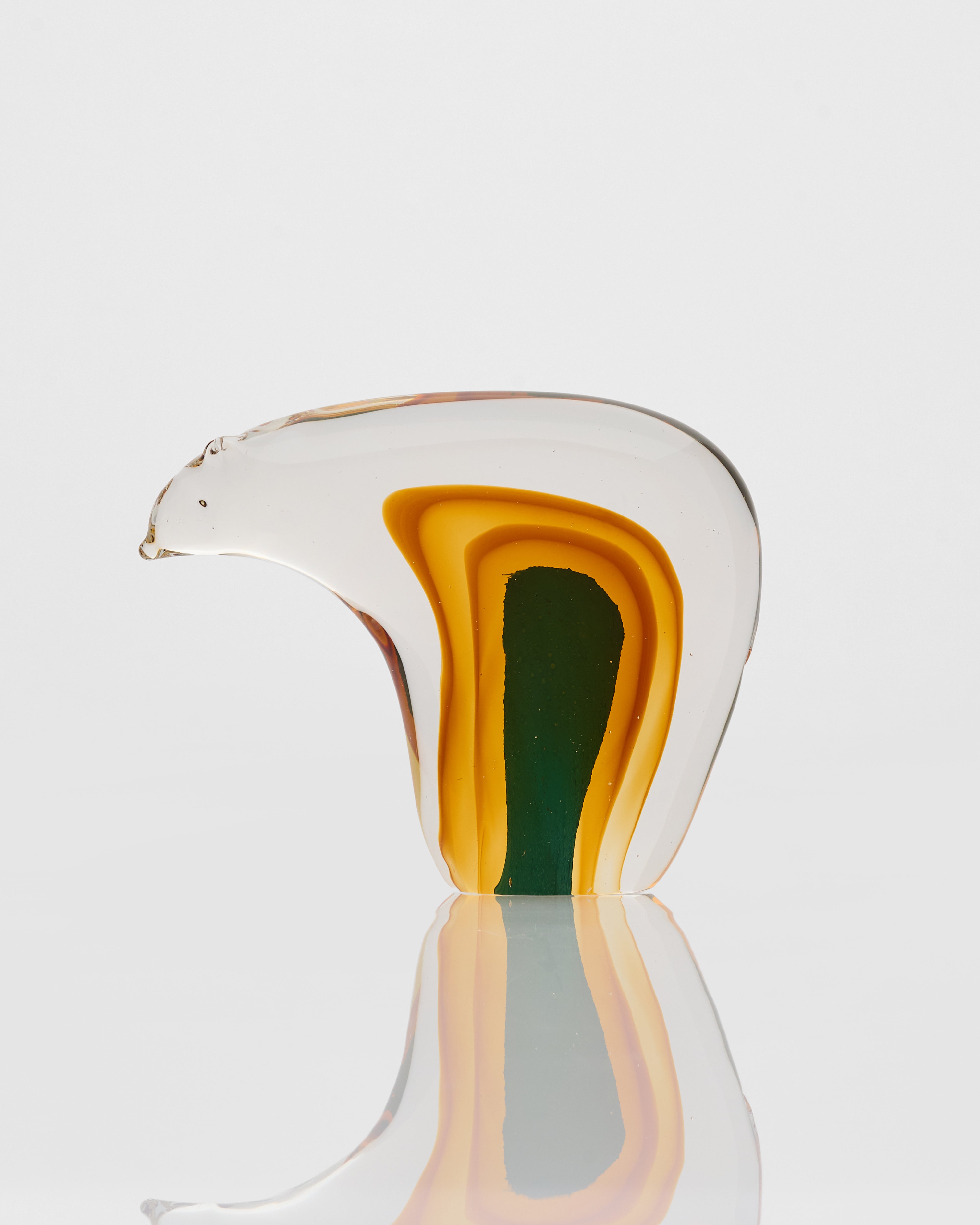 Glass sculpture with layered colors on a reflective surface
