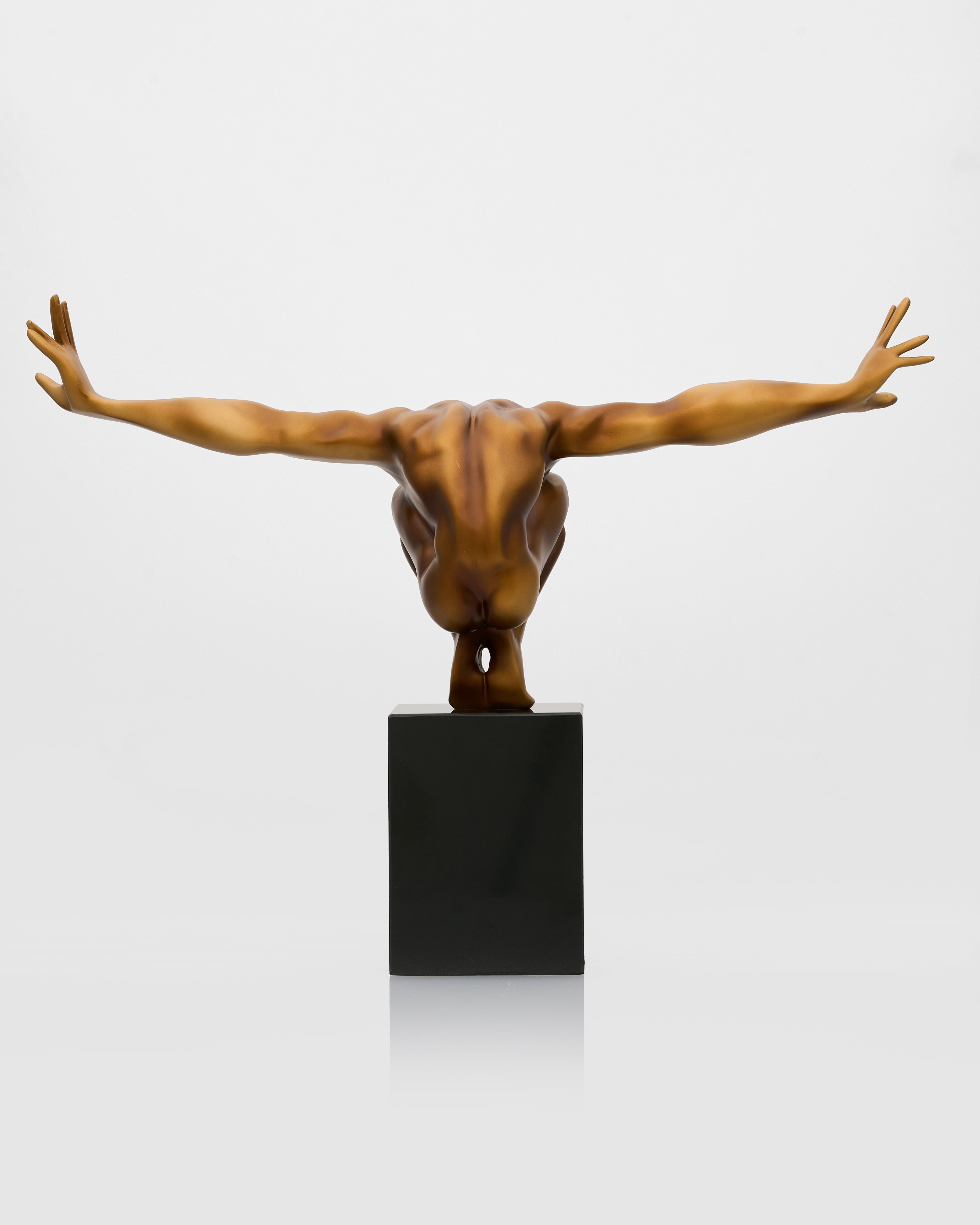 Bronze sculpture of a nude figure with outstretched arms on a black pedestal against a white background