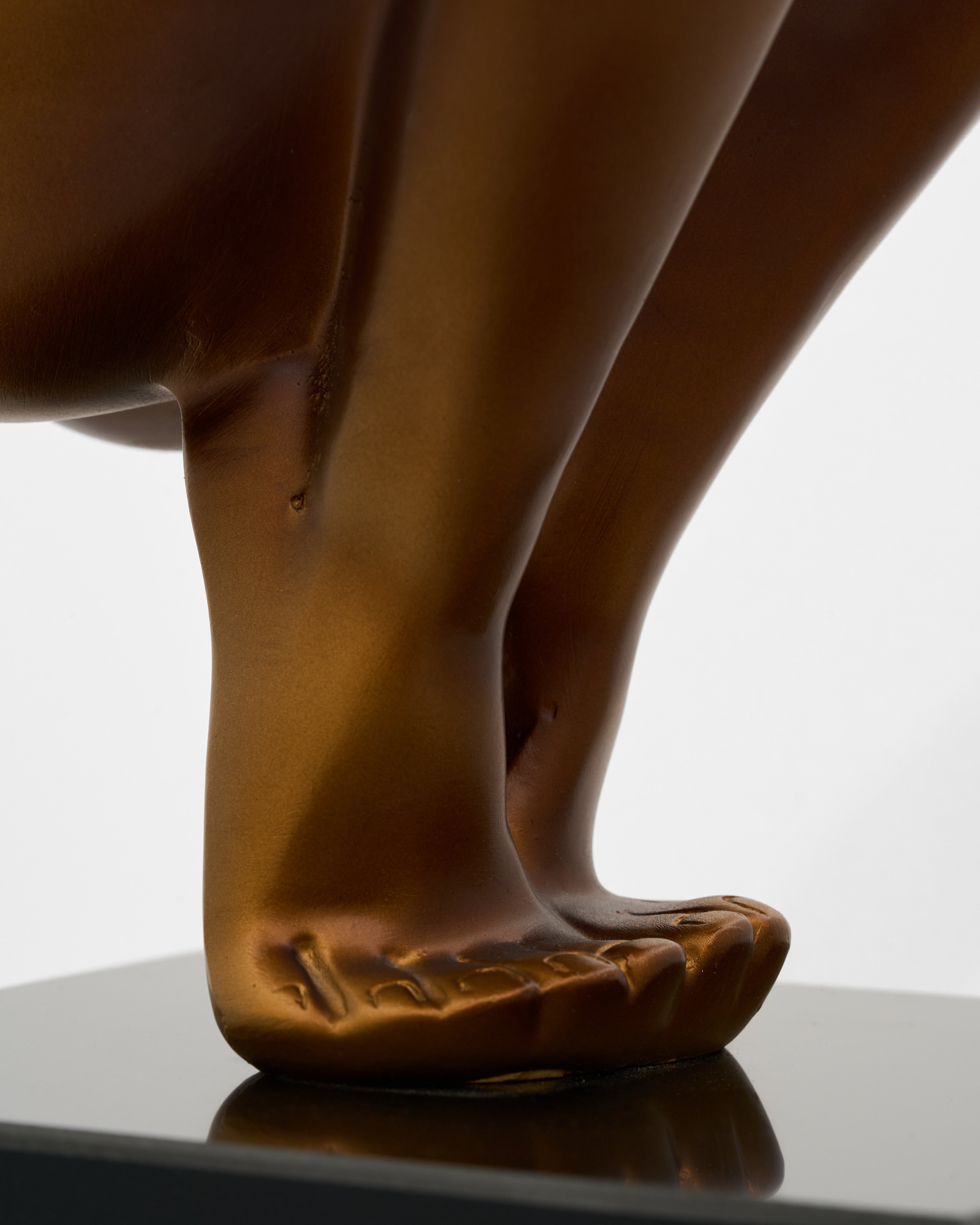 Bronze sculpture of a figure's feet on a reflective surface with a neutral background
