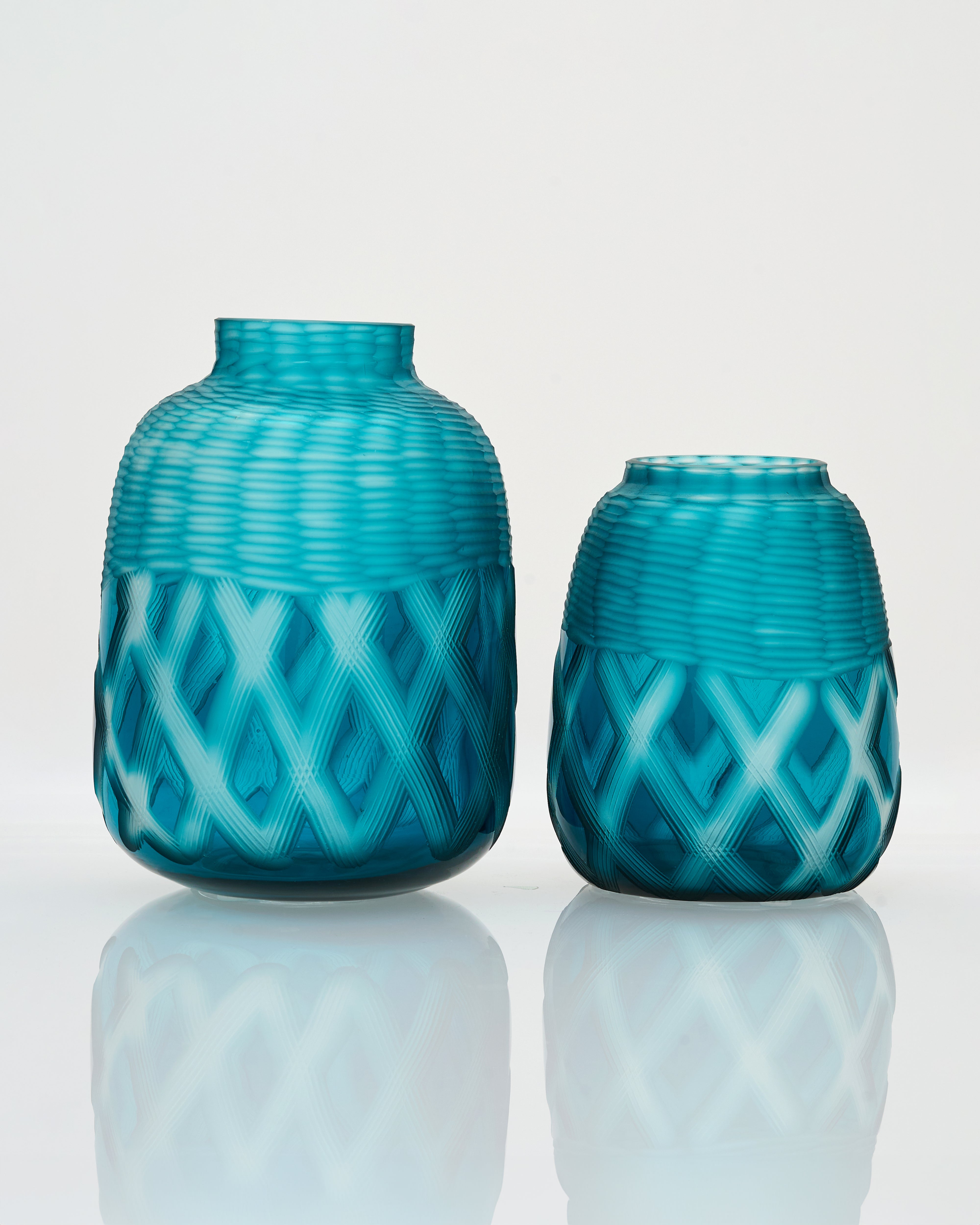 Two turquoise vases with a geometric pattern on a white background