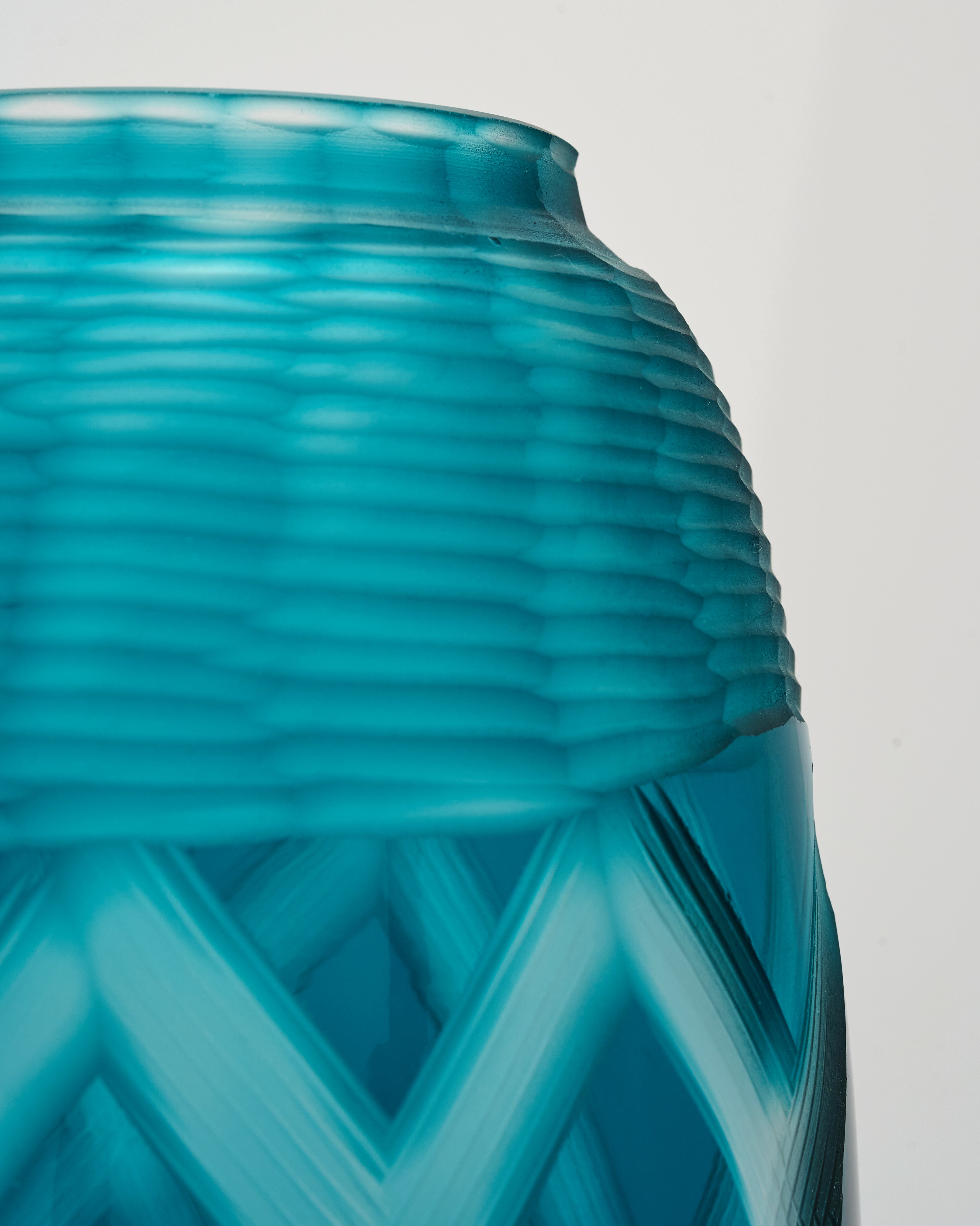 Close-up of a teal glass vase with textured design on a light gray background