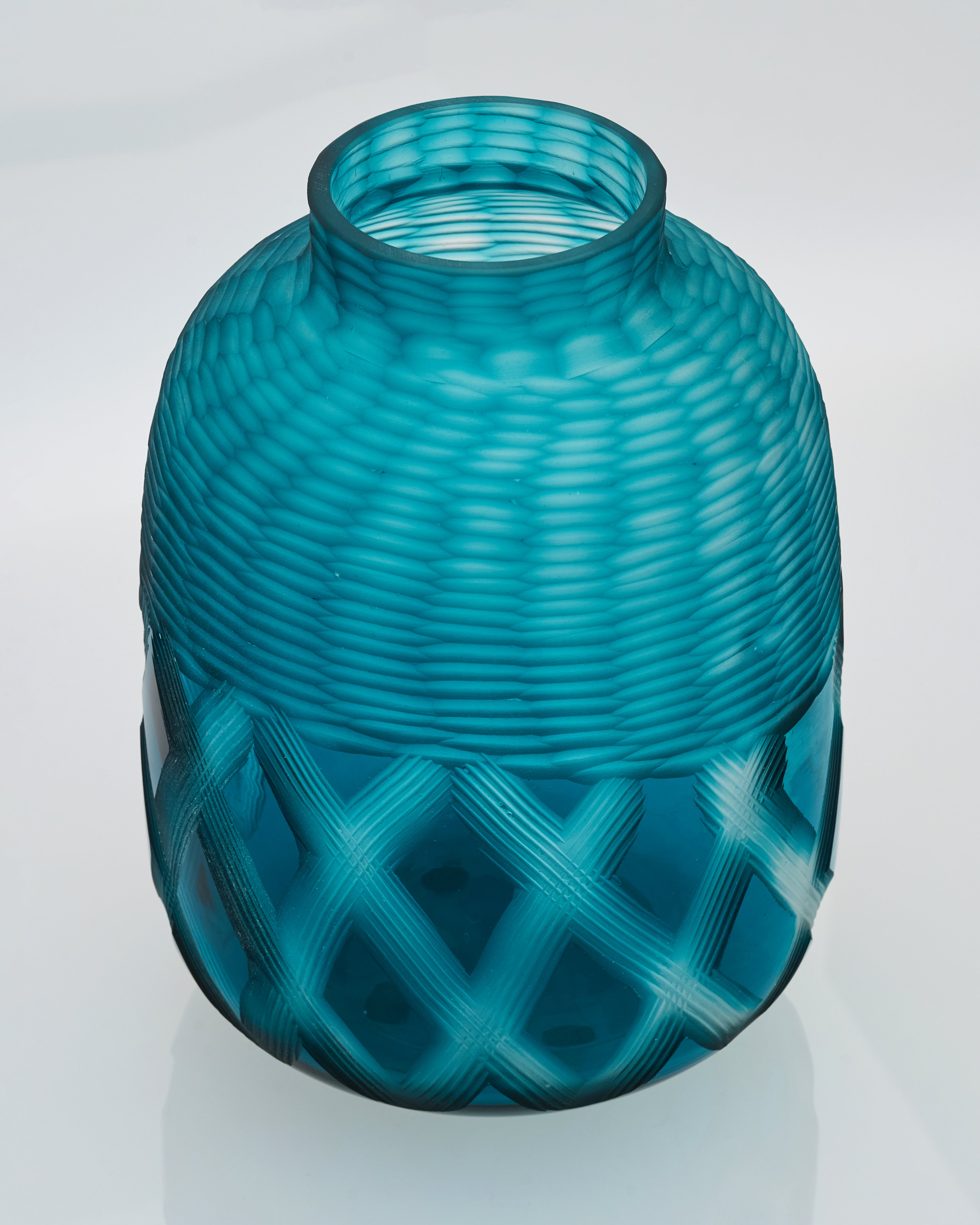 Teal glass vase with textured design on a white background