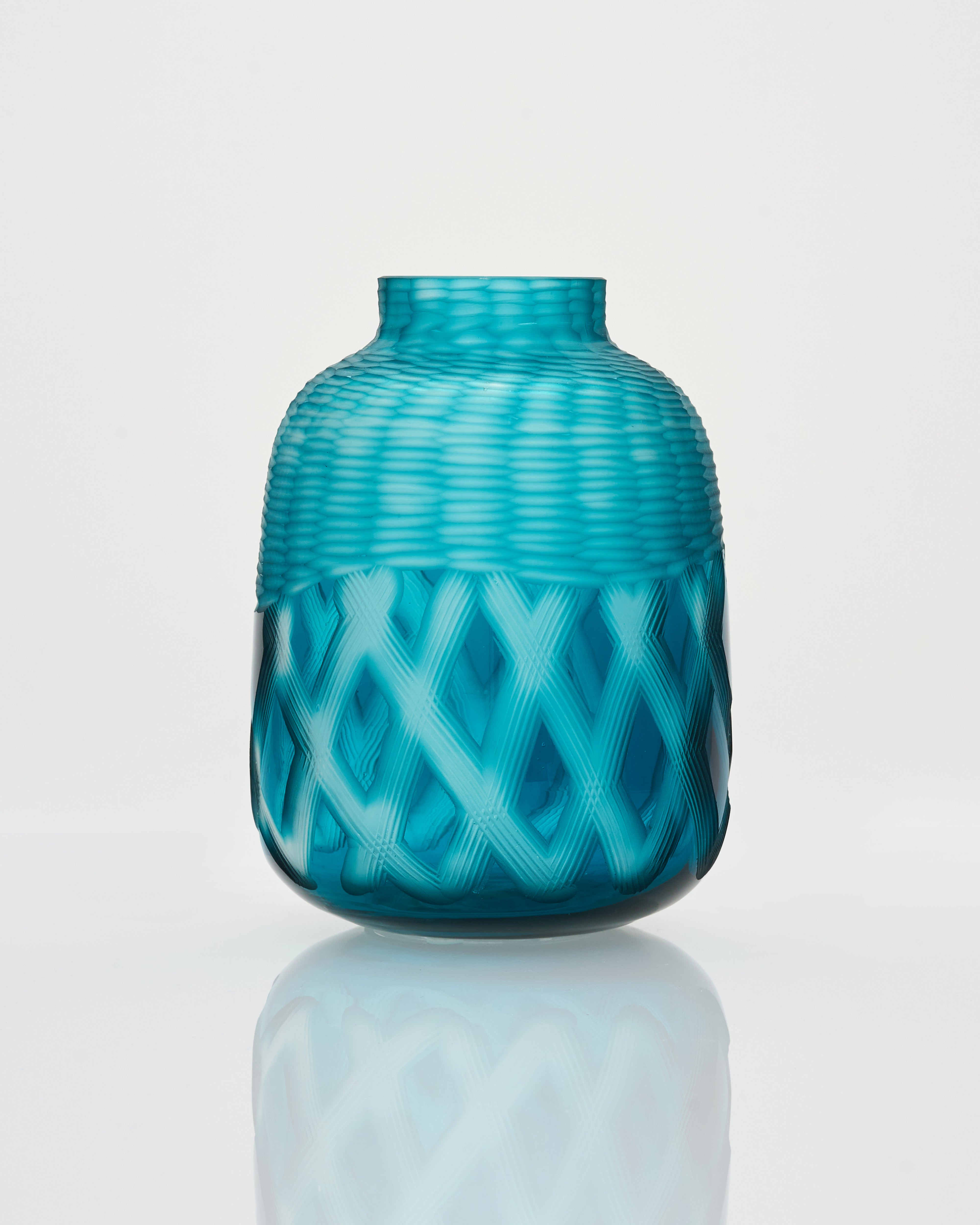 Turquoise glass vase with woven pattern on a white background azure color