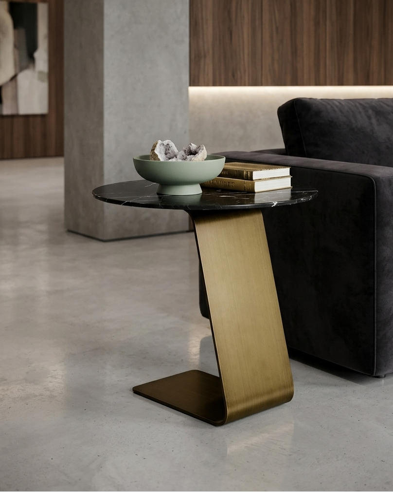 Modern side table with a gold base and black top in a living room setting.