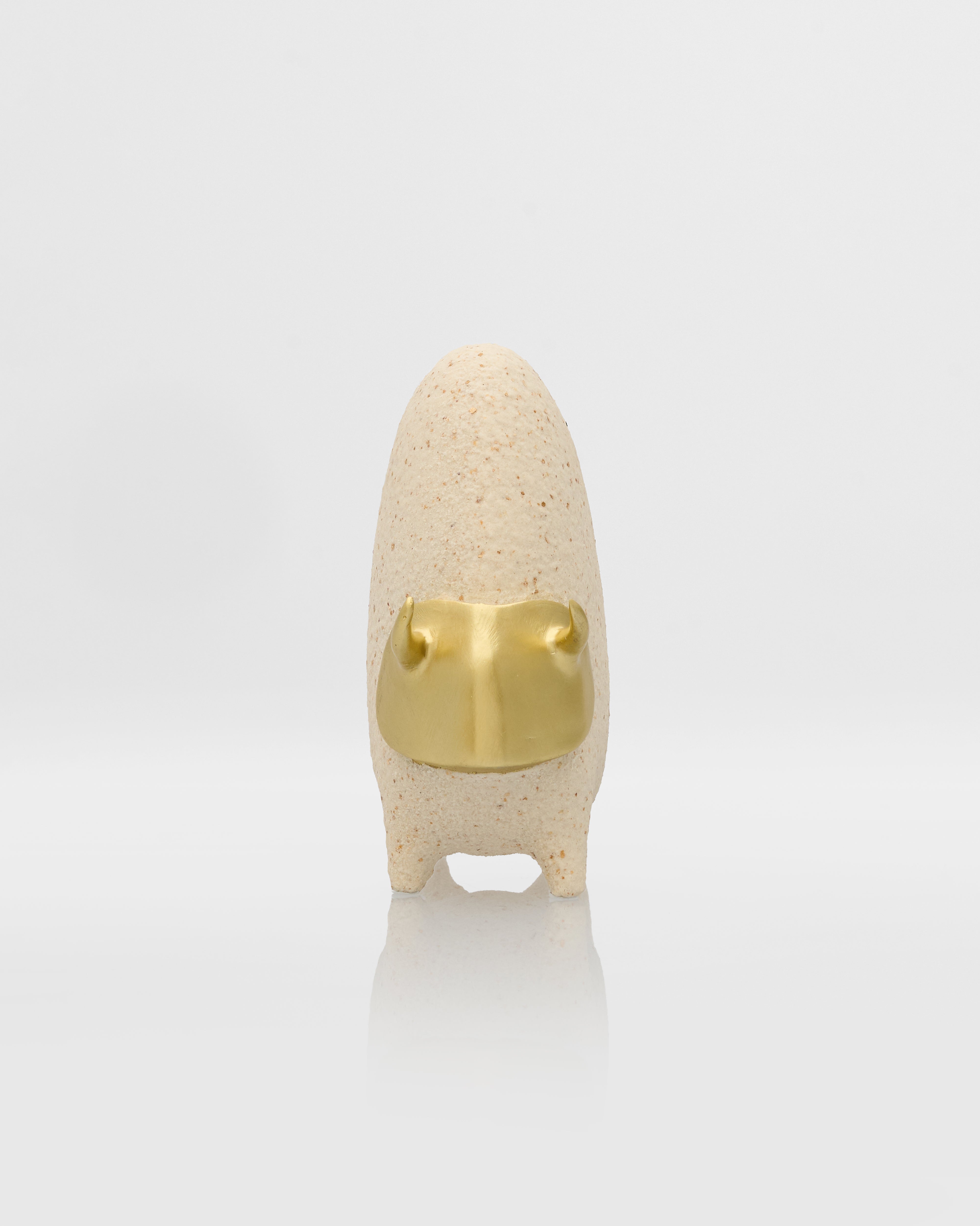 Small beige sculpture with a gold accent on a white background
