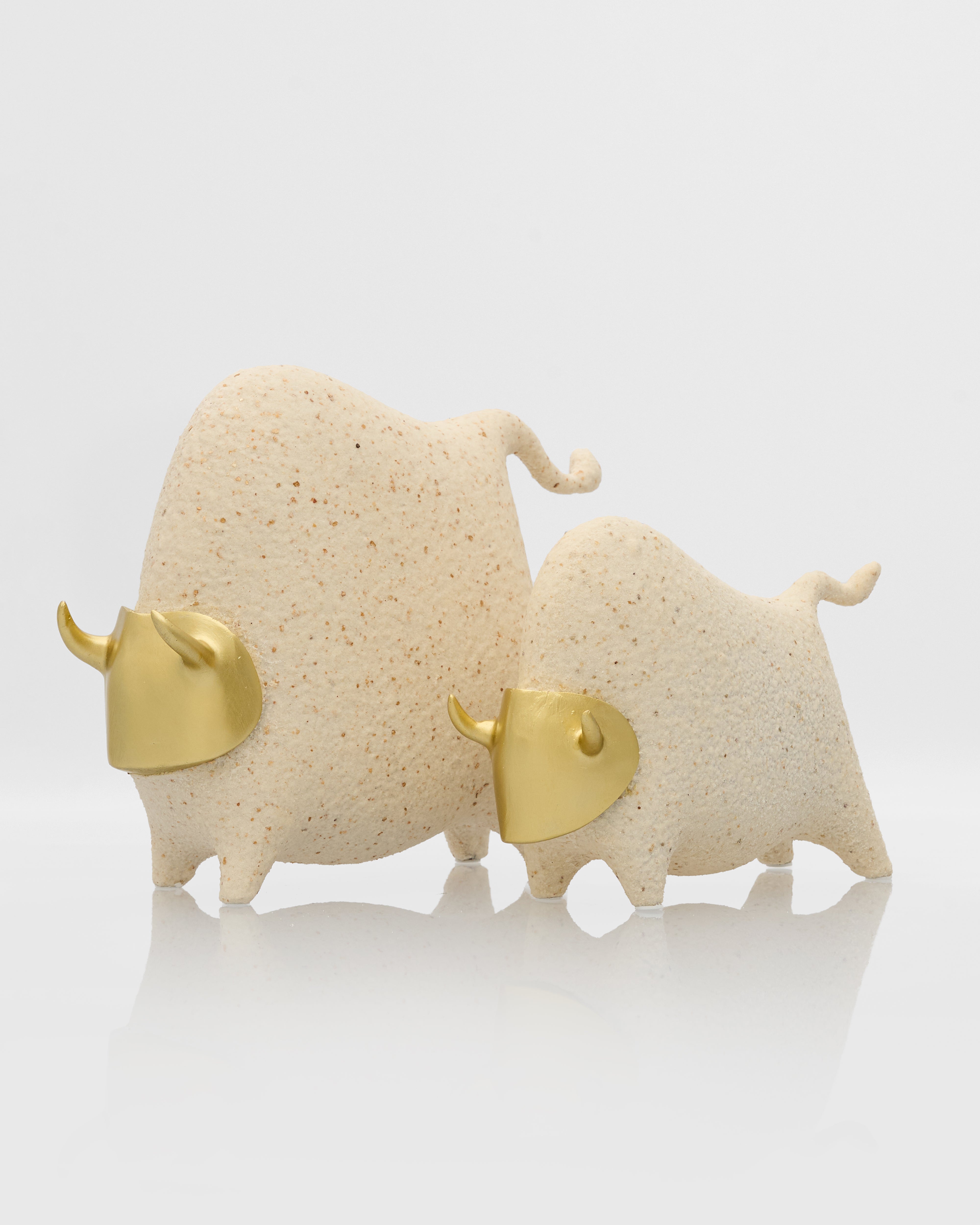Two ceramic bulls with gold accents on a white background