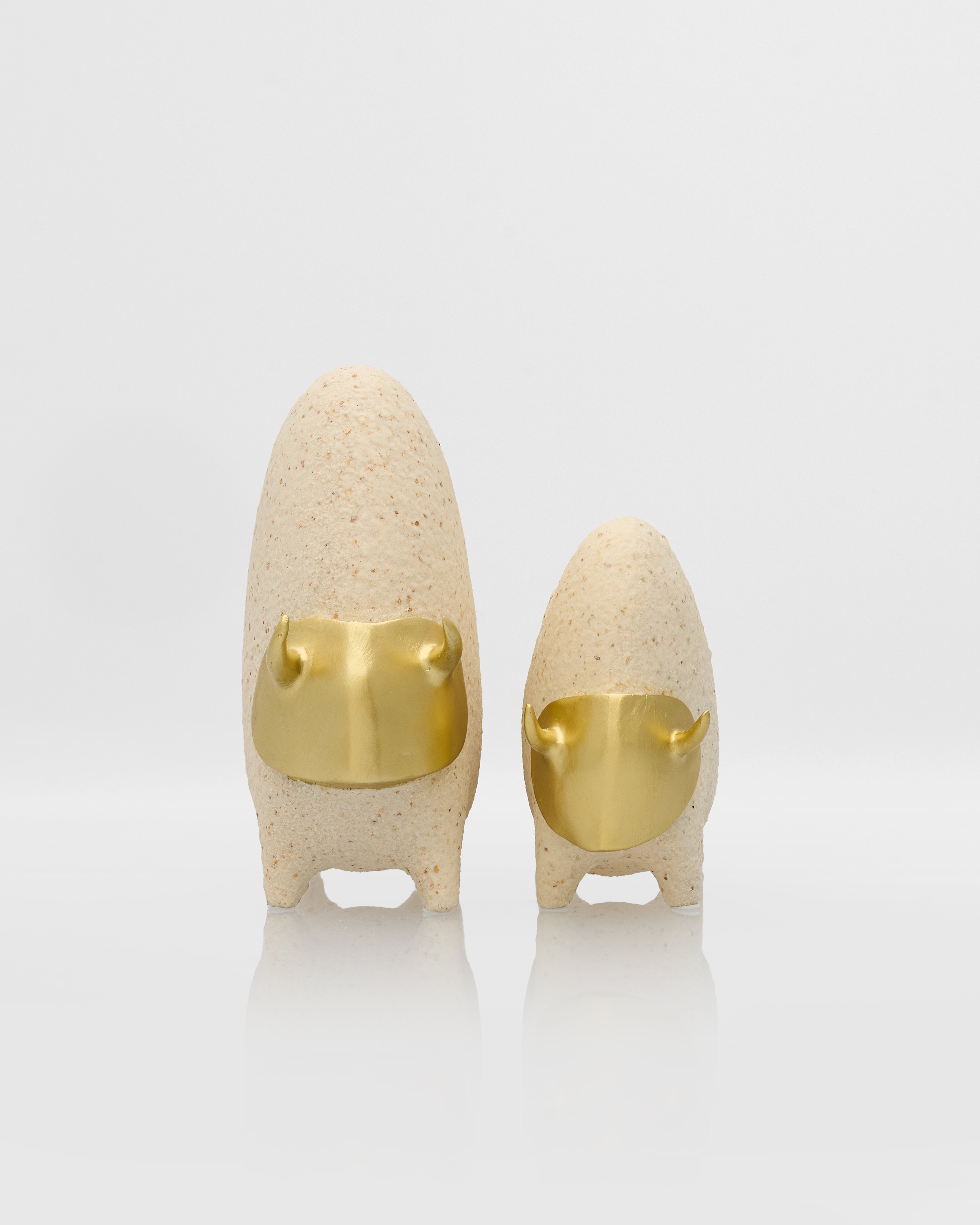 Two ceramic figures with gold faceplates on a white background
