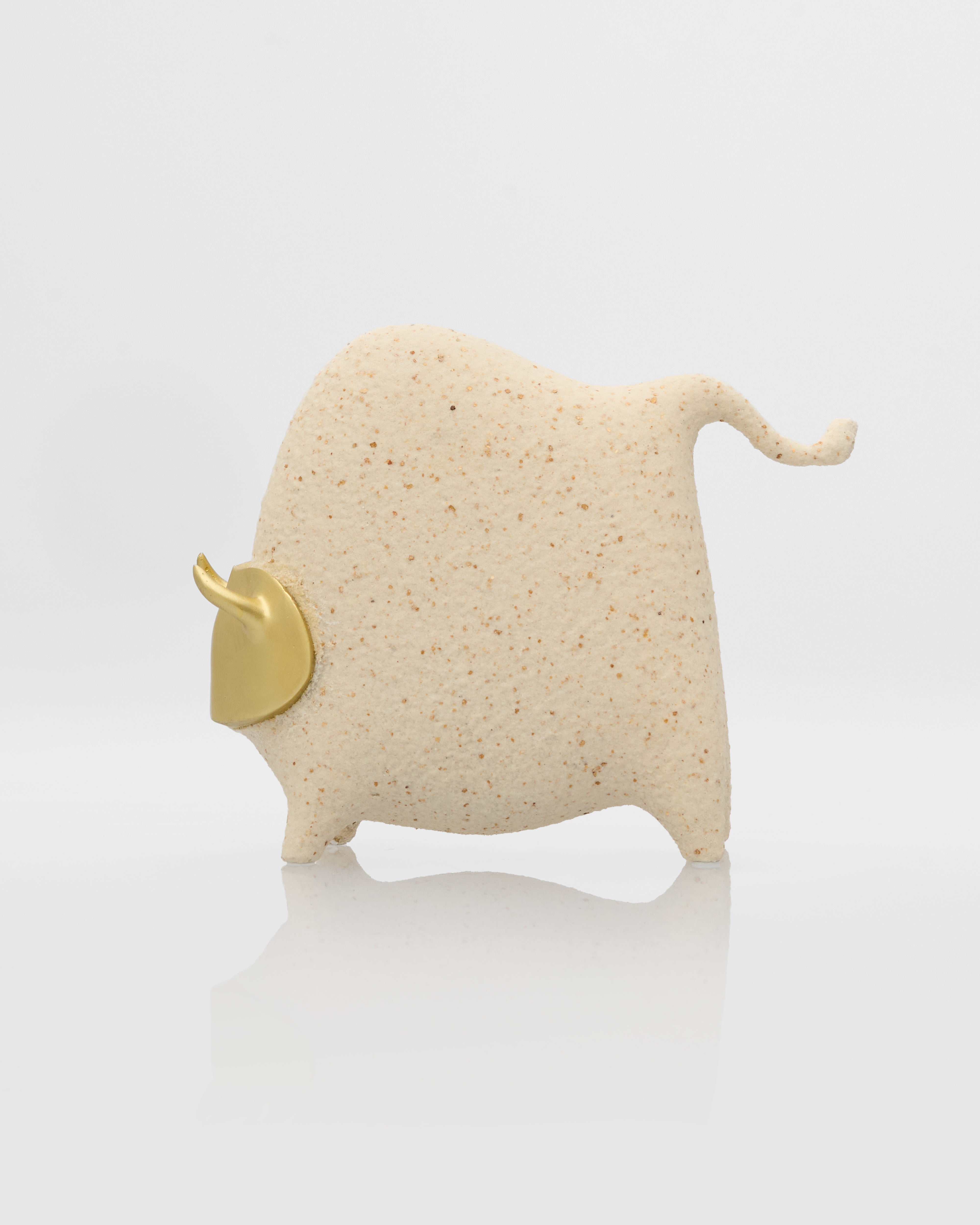 Small beige bull figurine with a gold horn on a white background