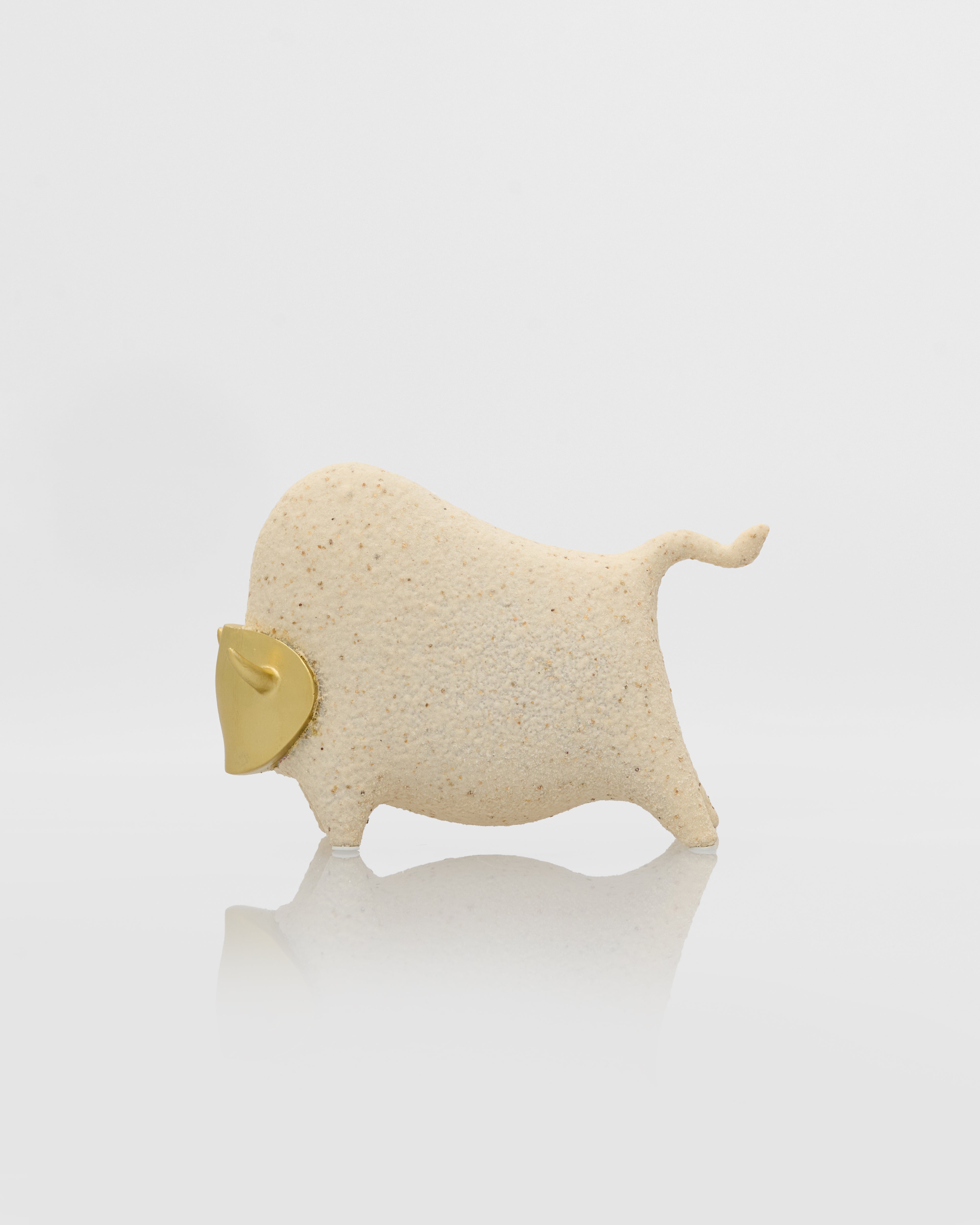 Small beige bull figurine on a white background