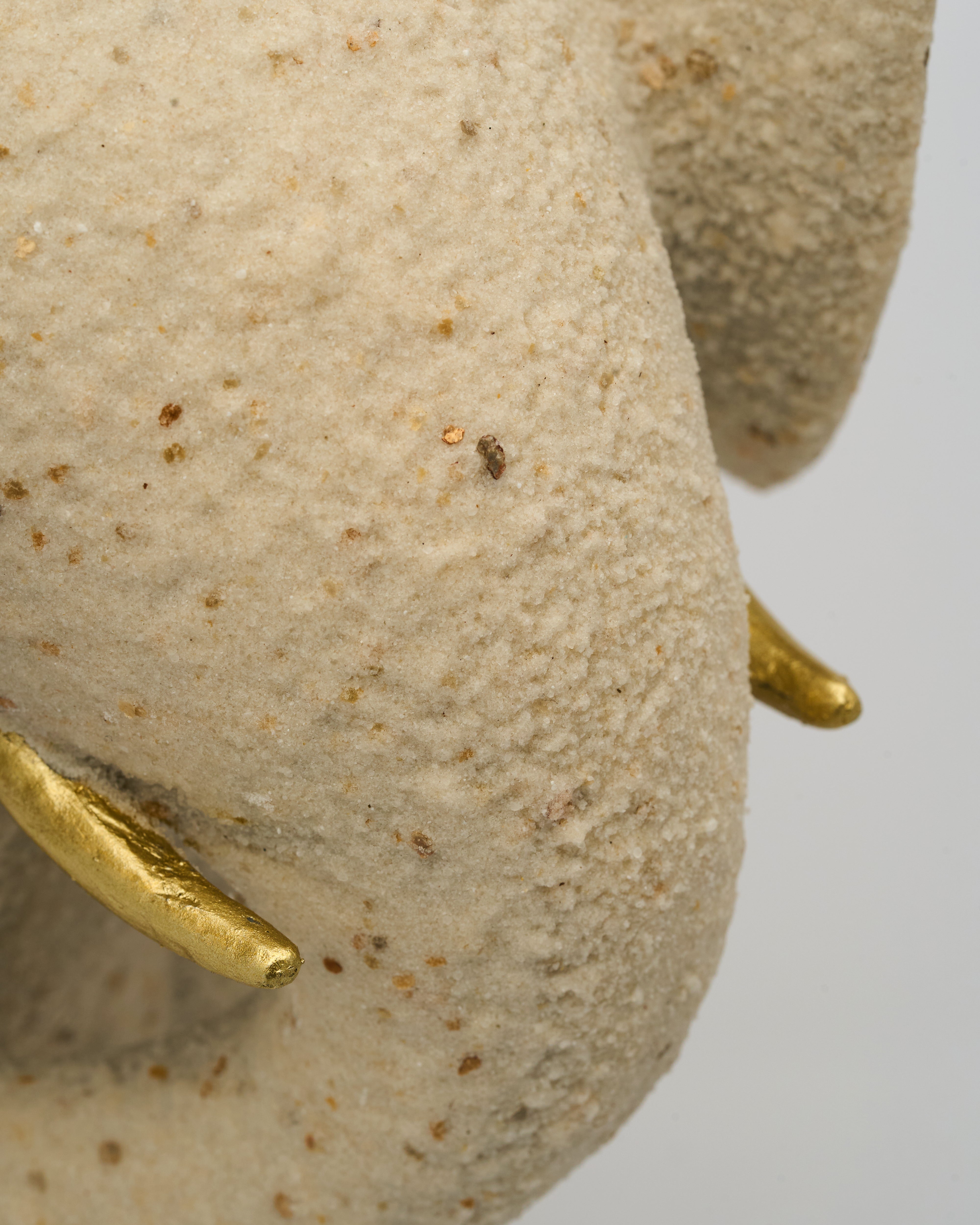 Close-up of a stone sculpture with gold accents on a plain background