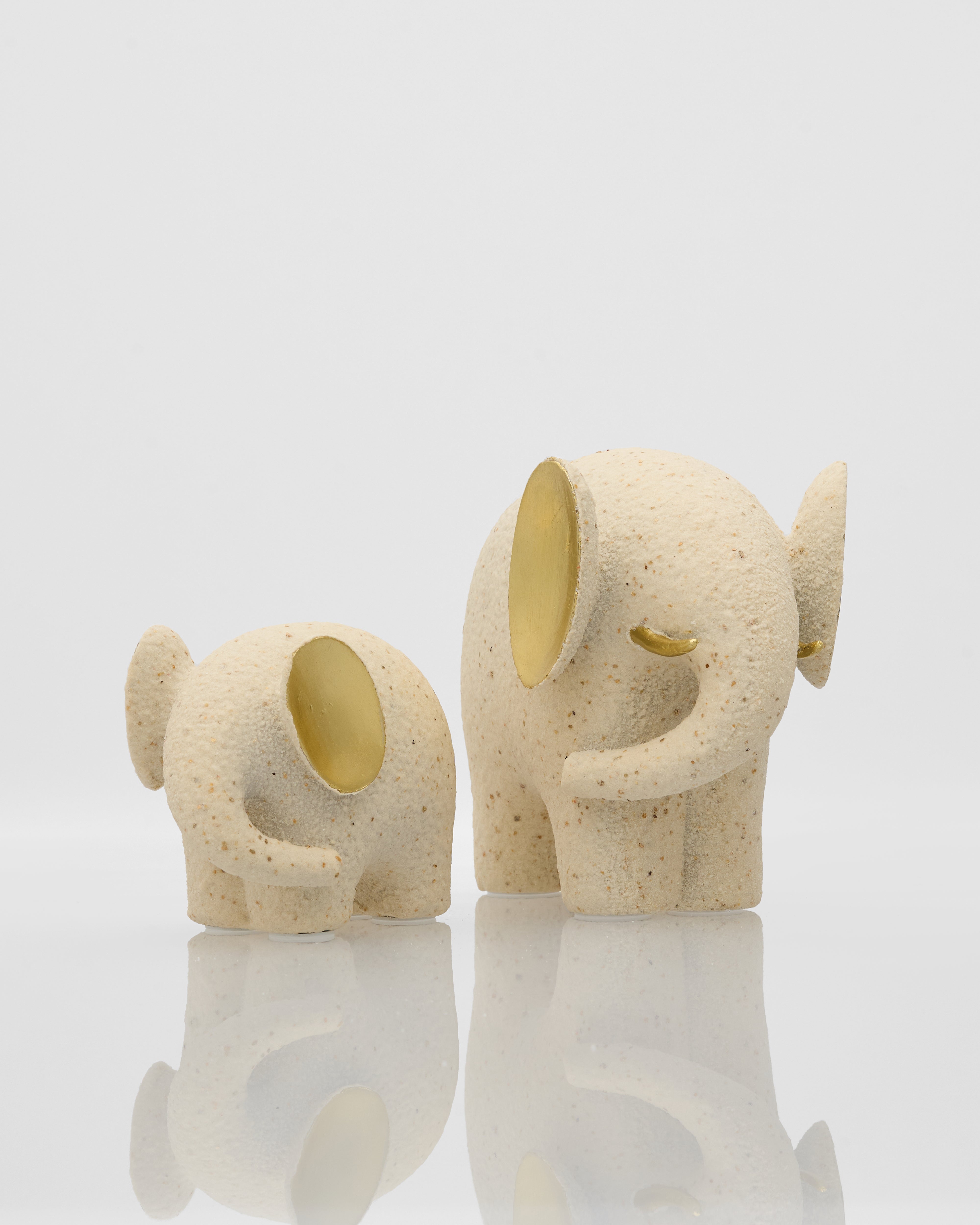 Two ceramic elephant figurines with gold interiors on a white background