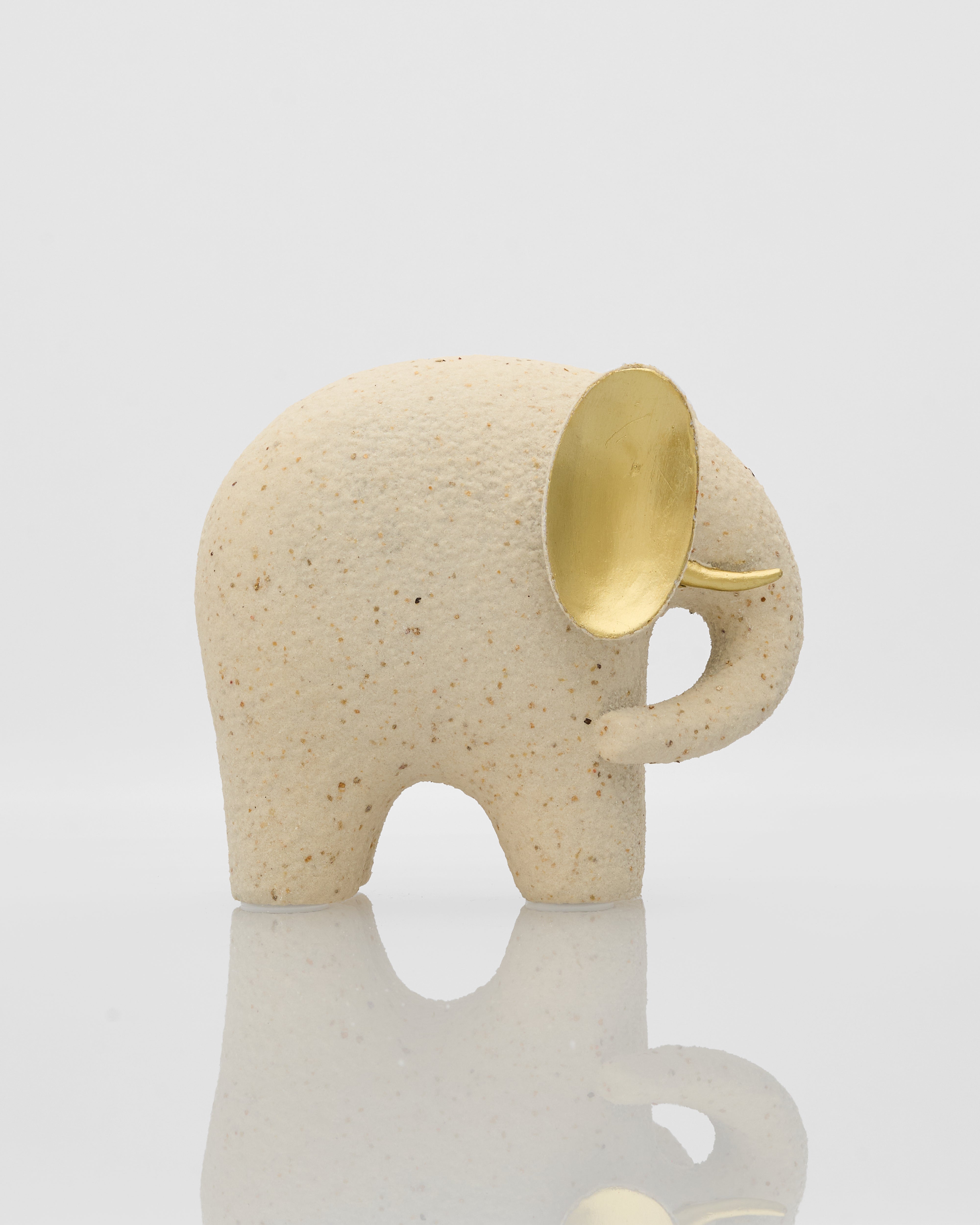 Ceramic elephant with a gold trunk on a light gray background