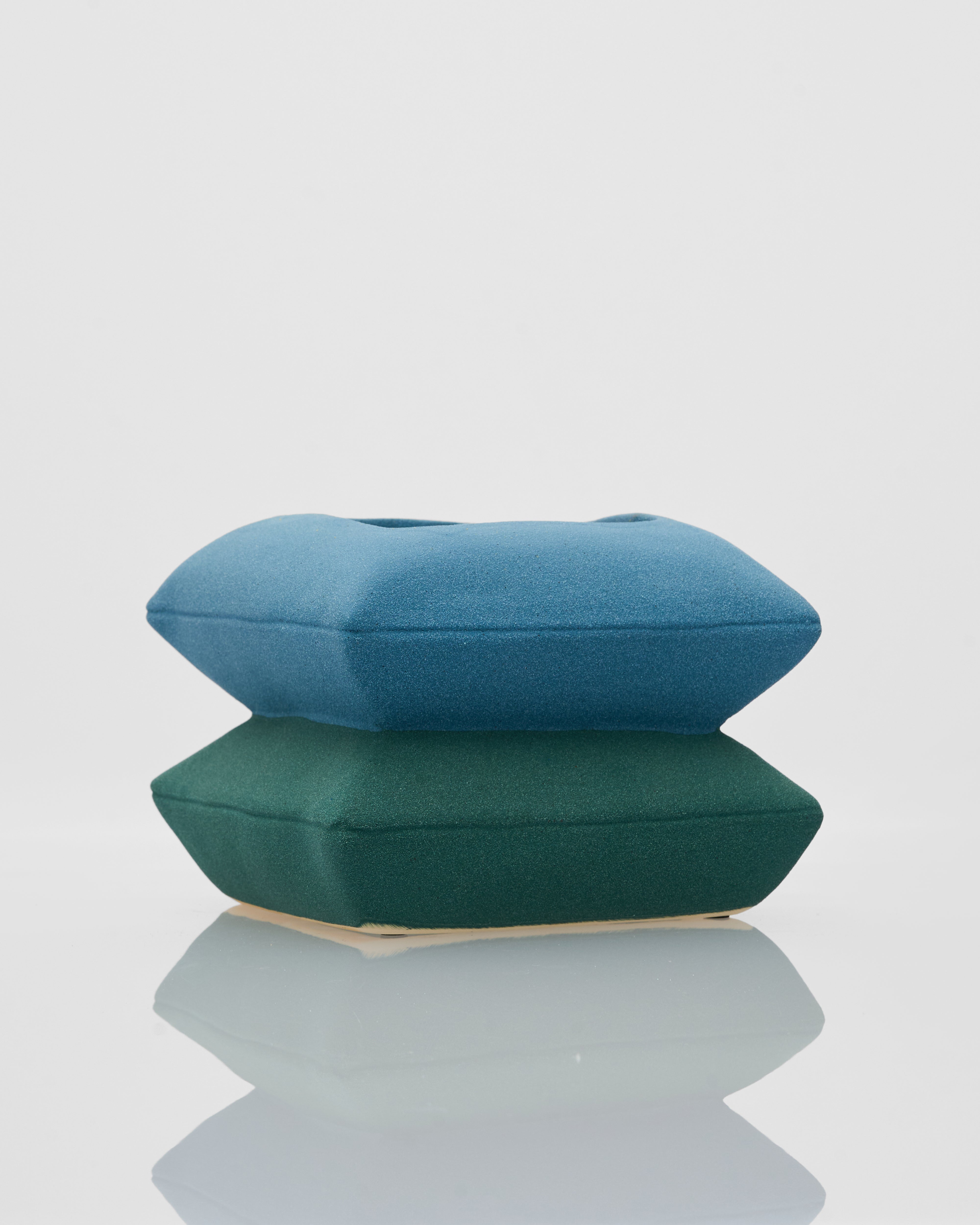 Two hexagonal cushions, one blue and one green, on a light gray background