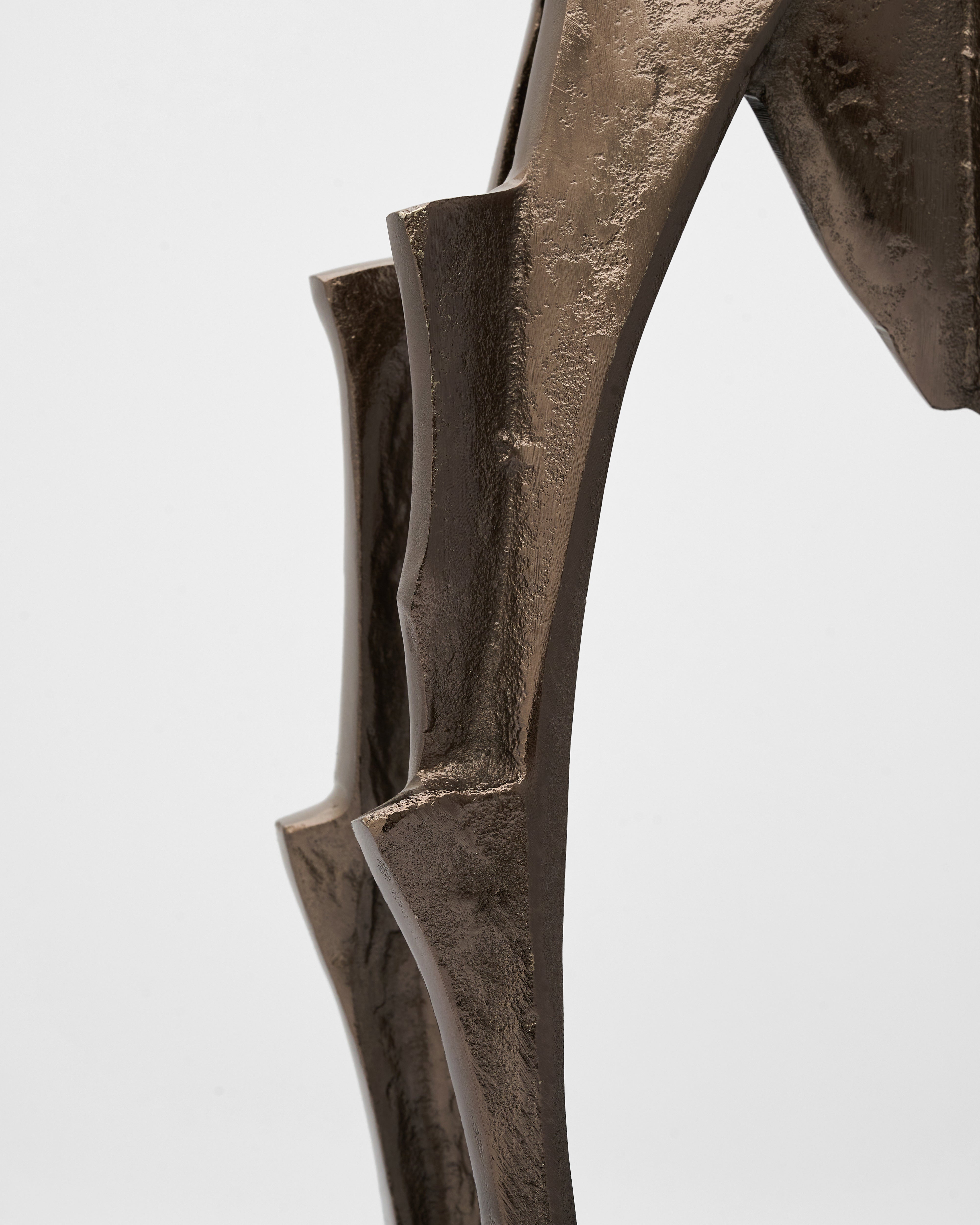 Bronze sculpture of a figure with a detailed arm on a white background