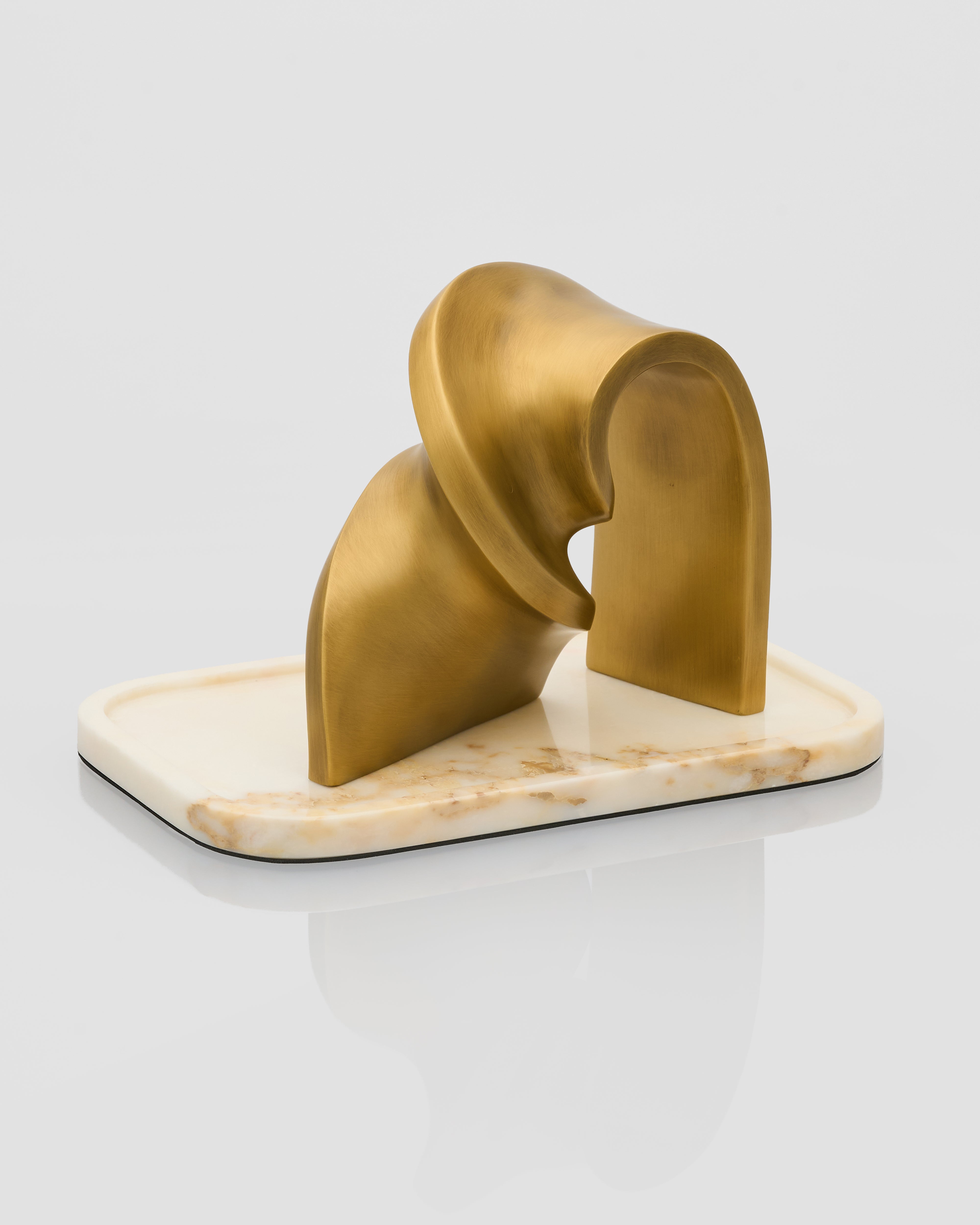 Gold decorative object on a marble base against a white background