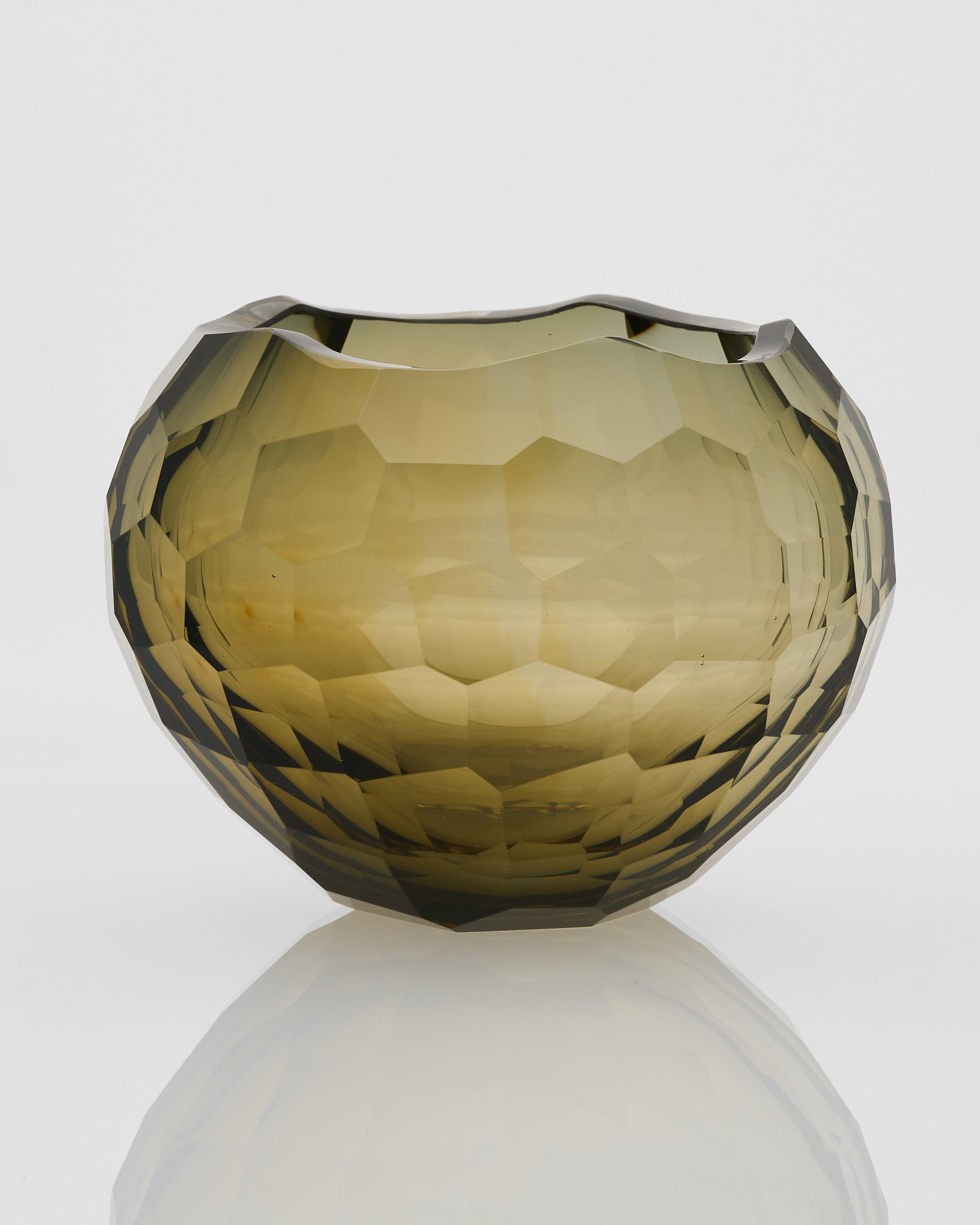 Faceted glass vase on a reflective surface with a light gray background