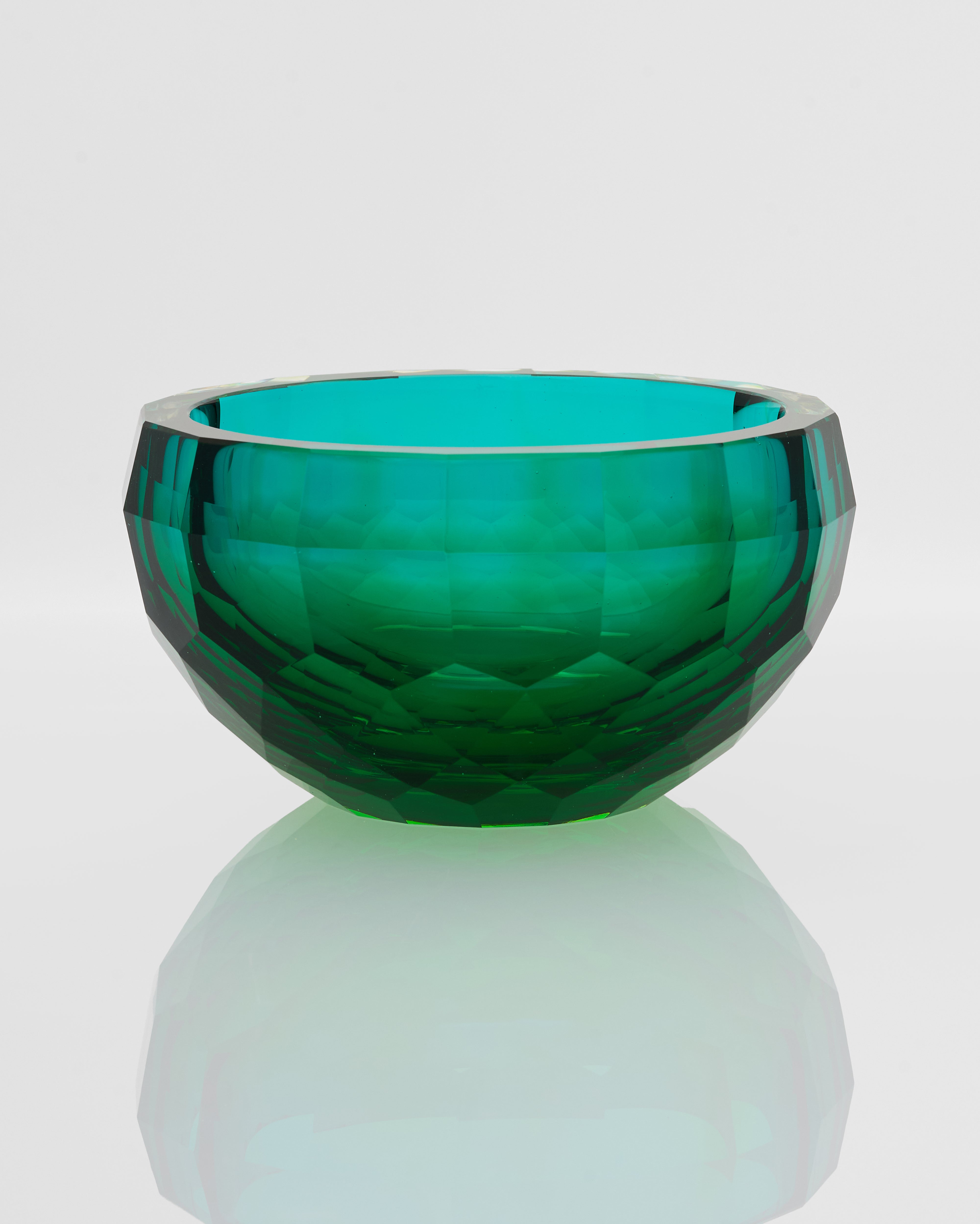 Faceted green glass bowl on a light gray background