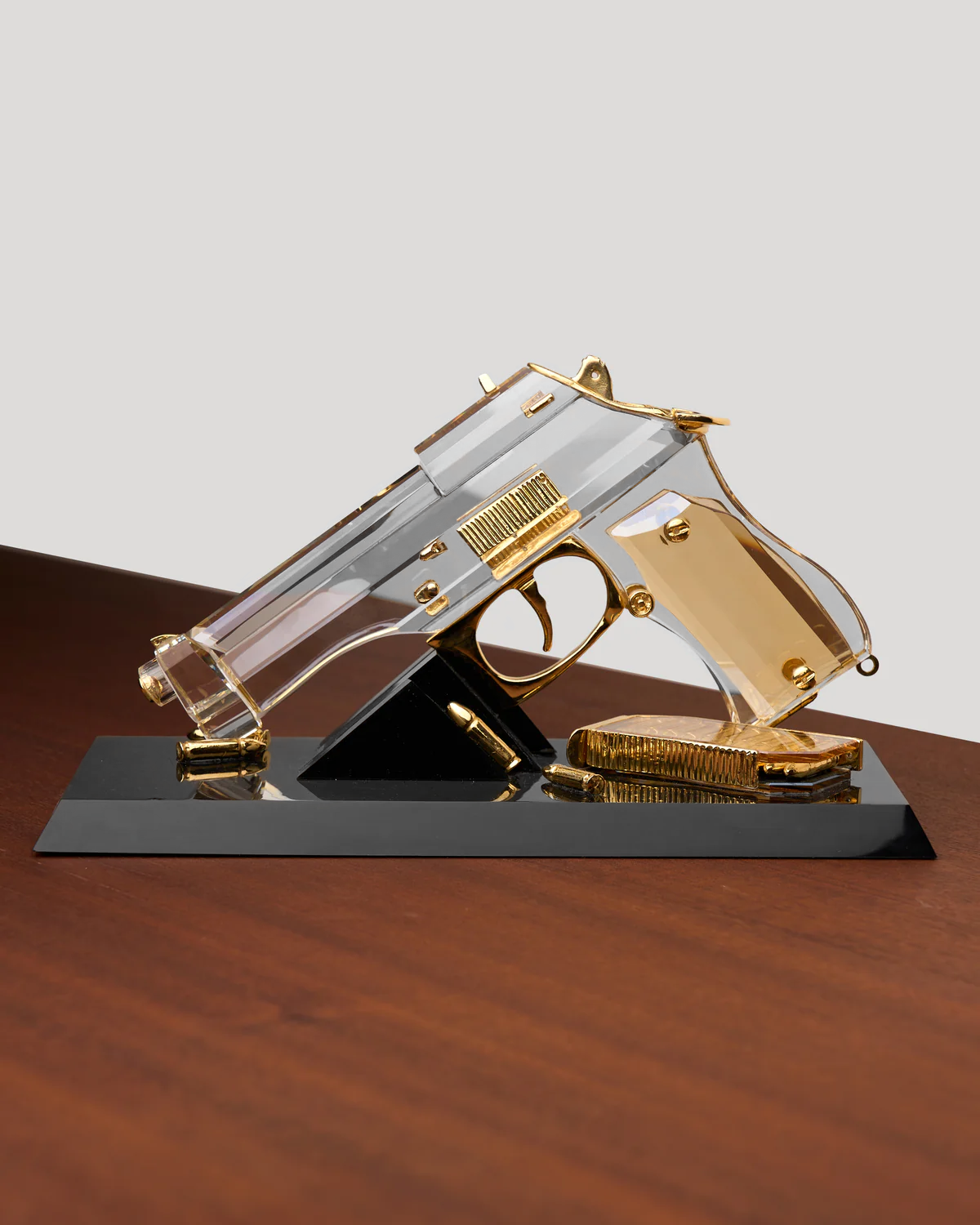 Decorative glass gun on a black base with a white background